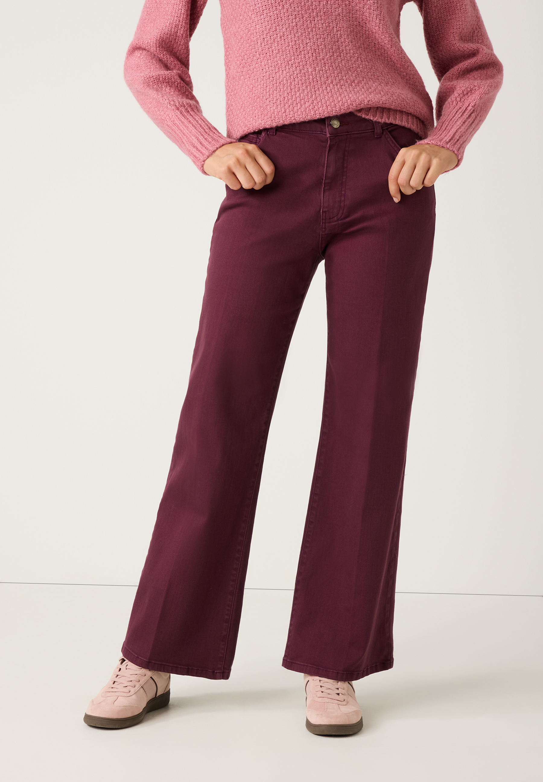 Eine Person trägt eine bordeauxfarbene MORE & MORE Jeans aus Denim und einen rosa Pullover, posierend vor einem hellen Hintergrund.