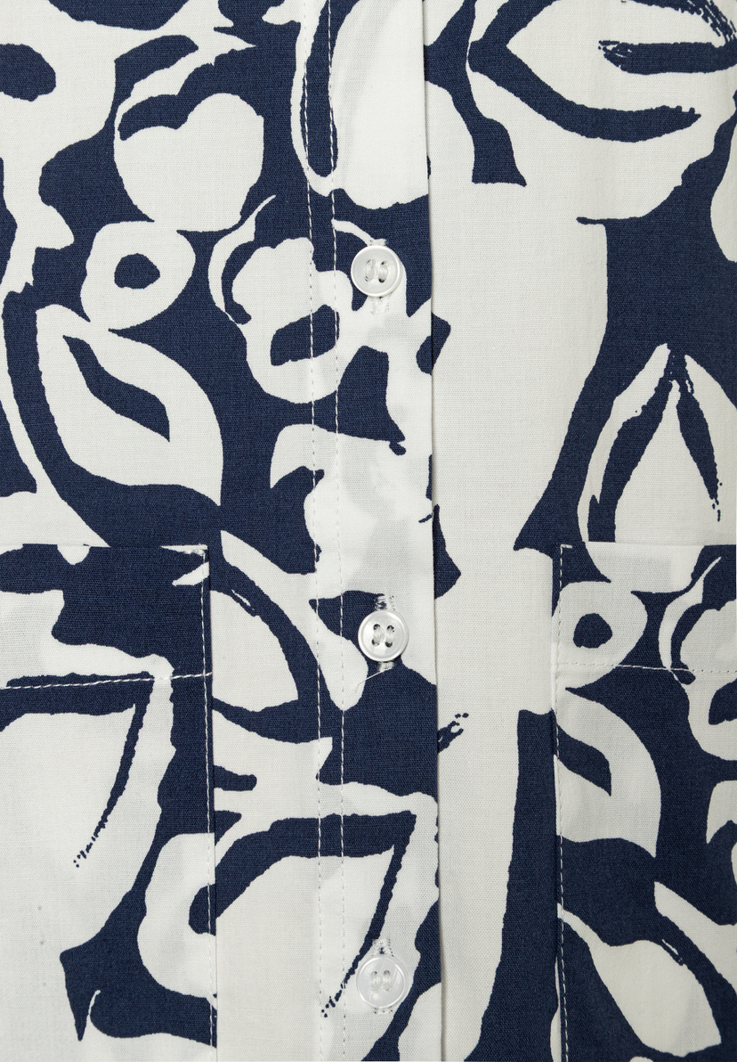 Nahaufnahme einer MORE & MORE Bluse mit blau-weißem Muster, Knopfleiste und Brusttasche. Nahaufnahme einer MORE & MORE Bluse mit blau-weißem Muster, Knopfleiste und Brusttasche.