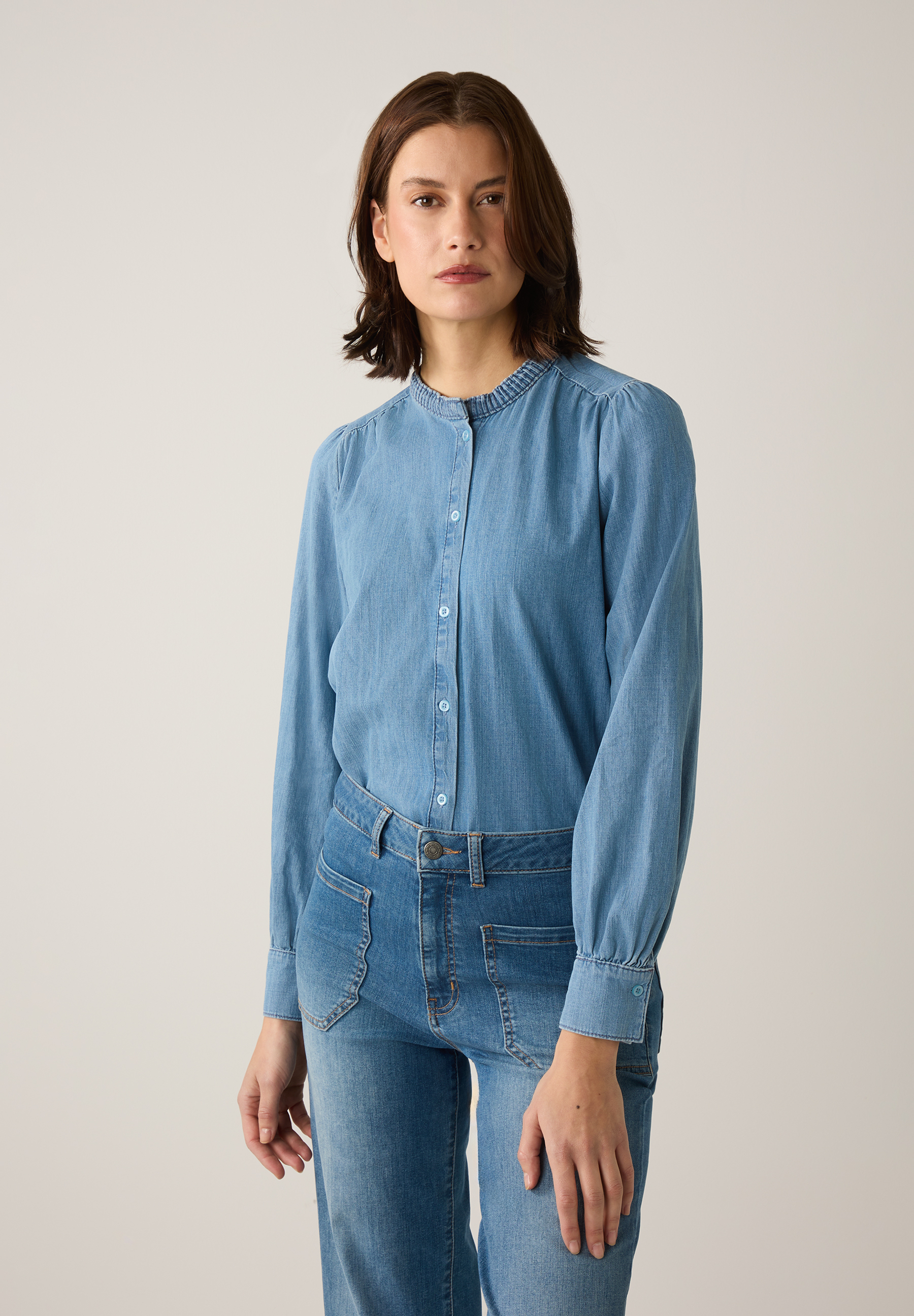 Eine Frau trägt ein Jeans-Ensemble von MORE & MORE, bestehend aus Bluse und Jeanshose. Eine Frau trägt ein Jeans-Ensemble von MORE & MORE, bestehend aus Bluse und Jeanshose.
