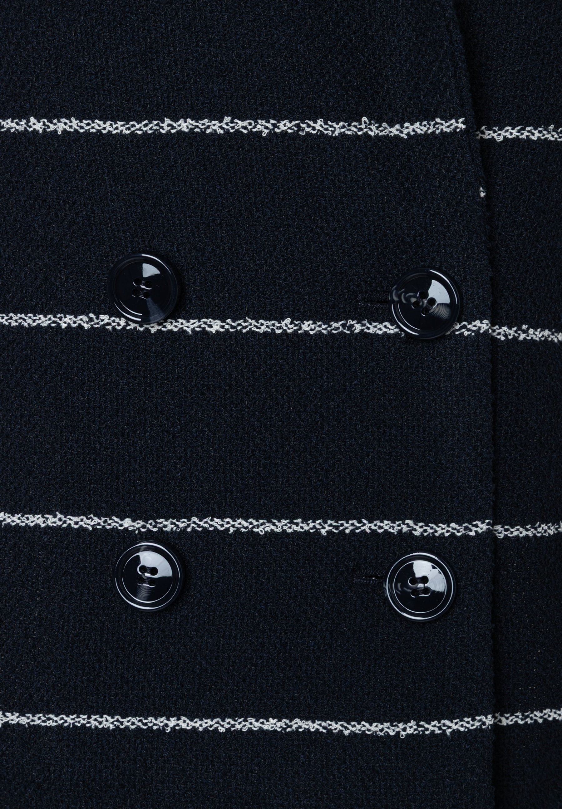 Detailansicht eines MORE & MORE Blazers mit Knöpfen und Bouclé-Streifen. Detailansicht eines MORE & MORE Blazers mit Knöpfen und Bouclé-Streifen.