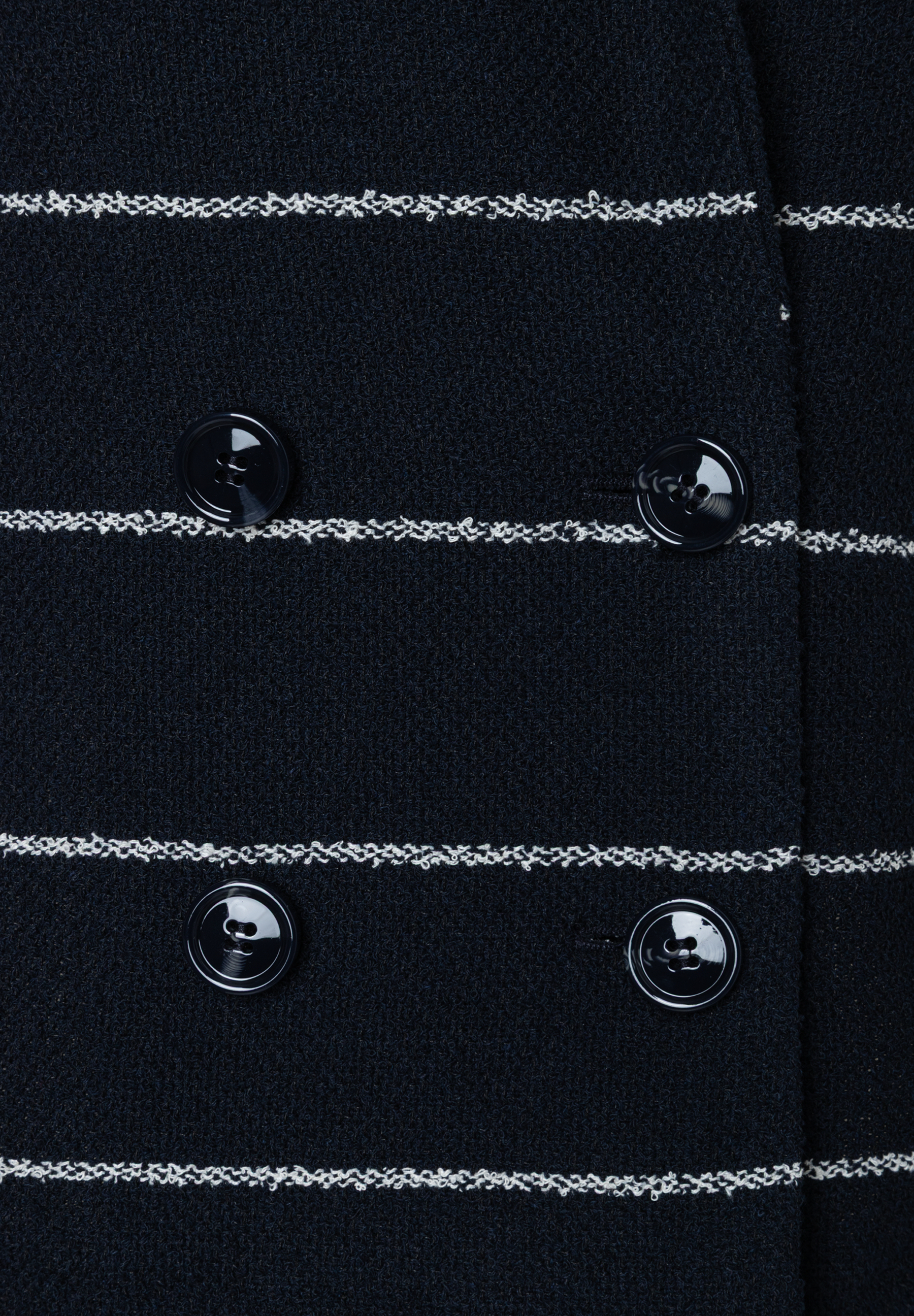 Detailansicht eines MORE & MORE Blazers mit Knöpfen und Bouclé-Streifen. Detailansicht eines MORE & MORE Blazers mit Knöpfen und Bouclé-Streifen.