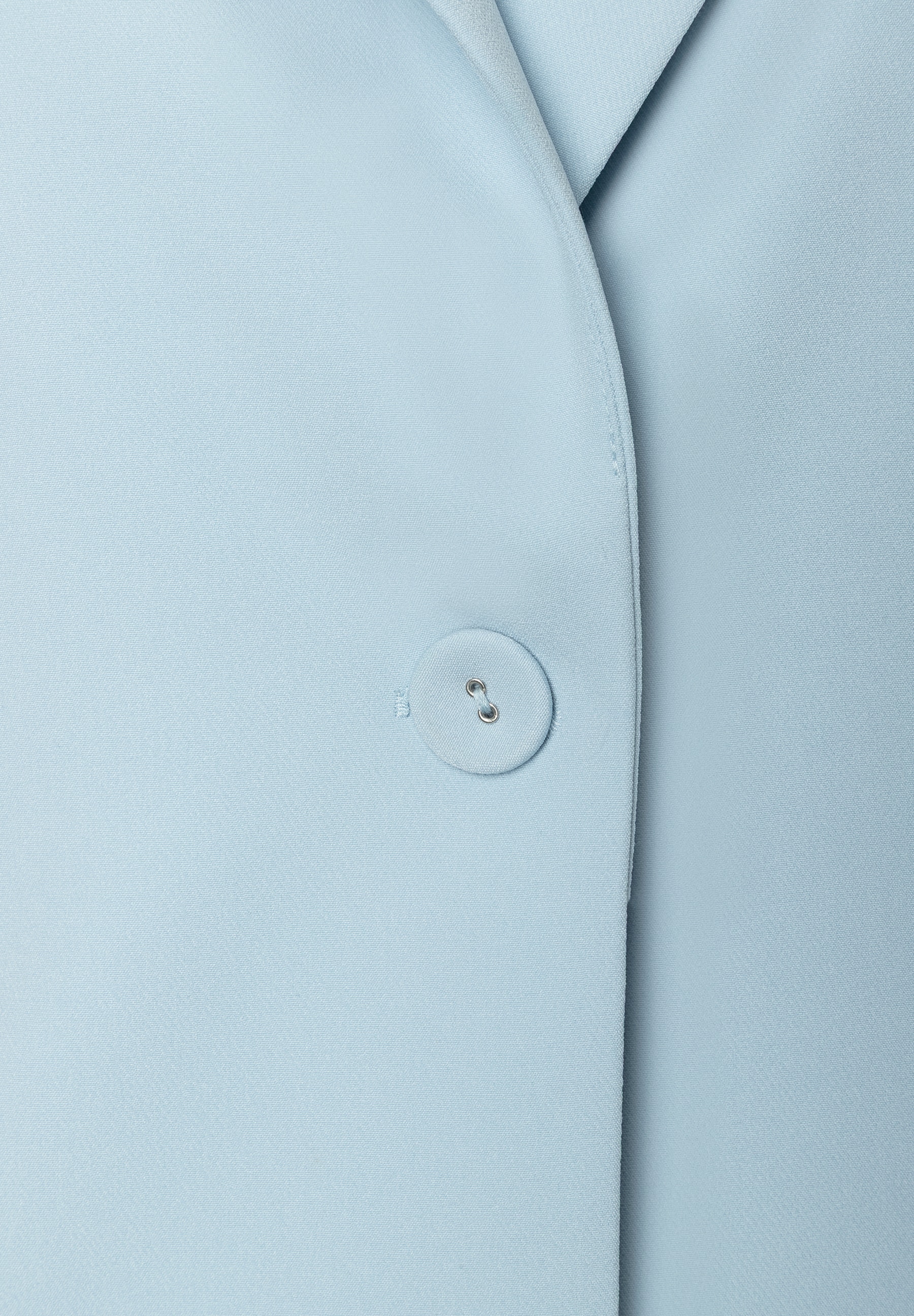 Detailansicht eines hellblauen MORE & MORE Blazers mit Knopf und Webware. Detailansicht eines hellblauen MORE & MORE Blazers mit Knopf und Webware.