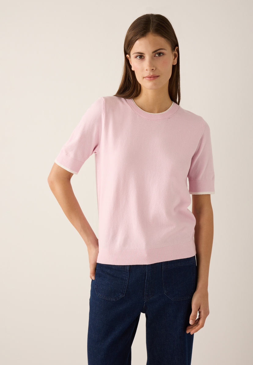 Eine Frau mit einem MORE & MORE Feinstrick-Oberteil mit kurzen Ärmeln und blauen Jeans. Eine Frau mit einem MORE & MORE Feinstrick-Oberteil mit kurzen Ärmeln und blauen Jeans.