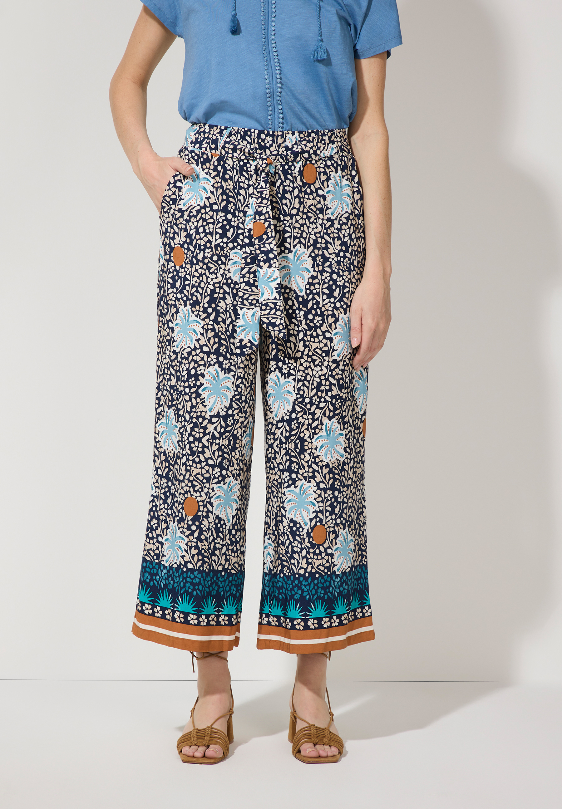 Eine Person trägt die MORE & MORE Hose/Jeans aus Viskose mit Blumenmuster. Sie hat einen angenehmen, kühlenden und fließenden Tragekomfort. Eine Person trägt die MORE & MORE Hose/Jeans aus Viskose mit Blumenmuster. Sie hat einen angenehmen, kühlenden und fließenden Tragekomfort.