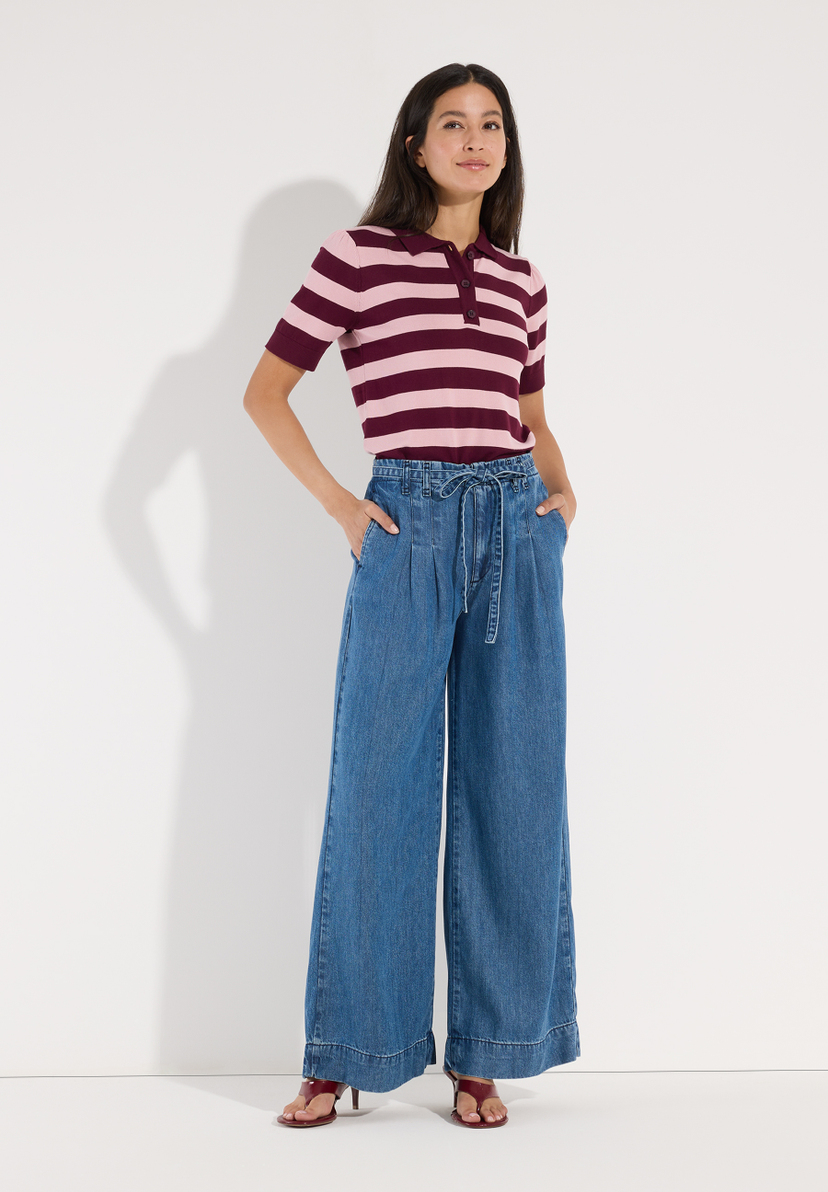 MORE & MORE Jeans: Junge Frau mit Sommersprossen, trägt weiße Bluse & weite blaue Denim-Jeans. Sitzt leicht schräg. MORE & MORE Jeans: Junge Frau mit Sommersprossen, trägt weiße Bluse & weite blaue Denim-Jeans. Sitzt leicht schräg.