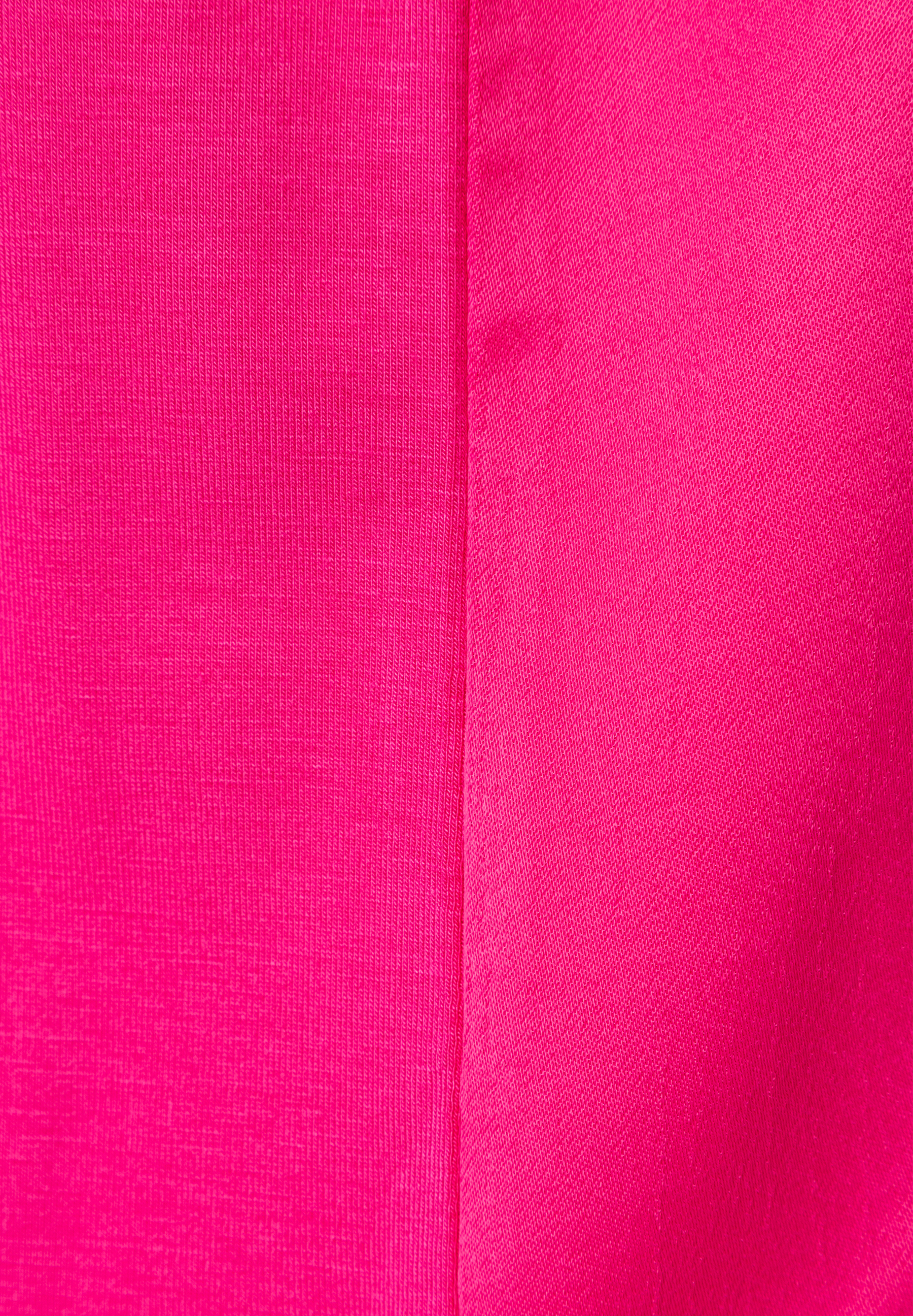 Nahaufnahme eines pinken MORE & MORE T-Shirts/Tops, das eine markante Textur zeigt. Nahaufnahme eines pinken MORE & MORE T-Shirts/Tops, das eine markante Textur zeigt.