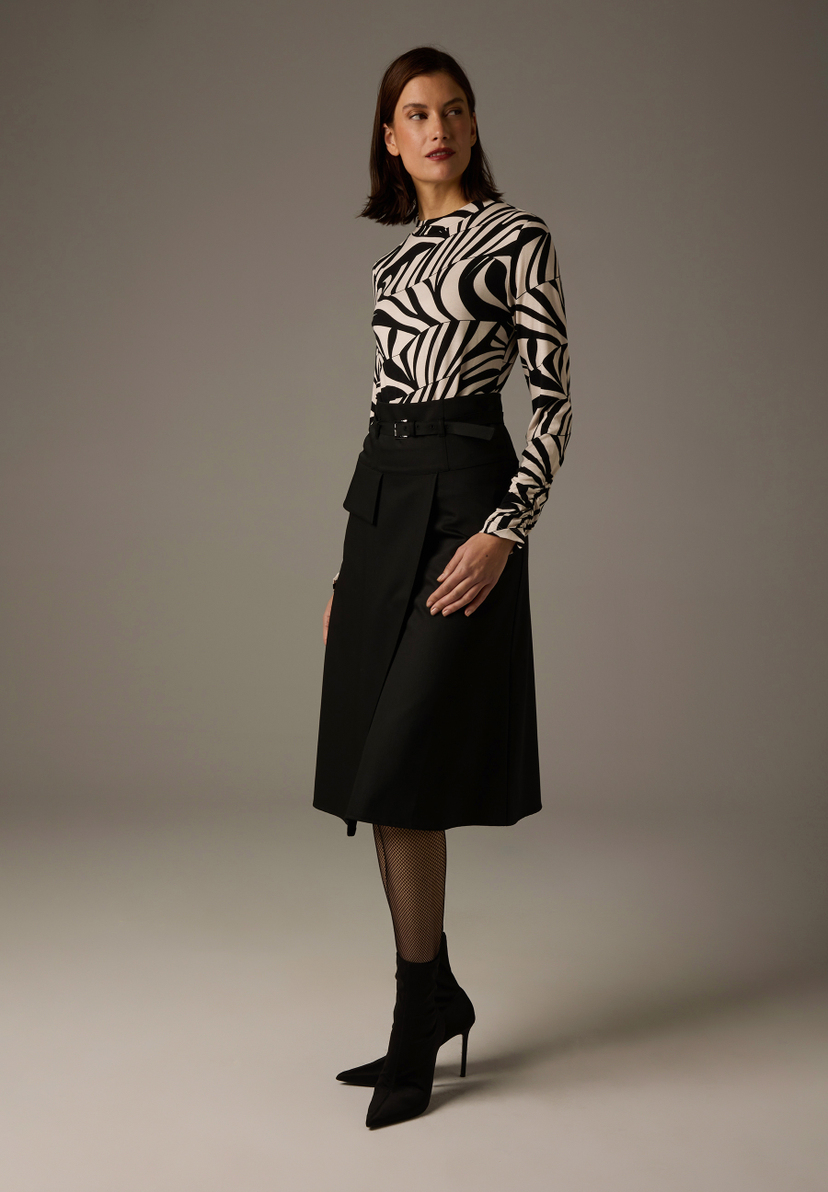 Eine Frau in einem MORE & MORE Oberteil mit Zebra-Print, einem schwarzen Rock und Stiefeln. Eine Frau in einem MORE & MORE Oberteil mit Zebra-Print, einem schwarzen Rock und Stiefeln.