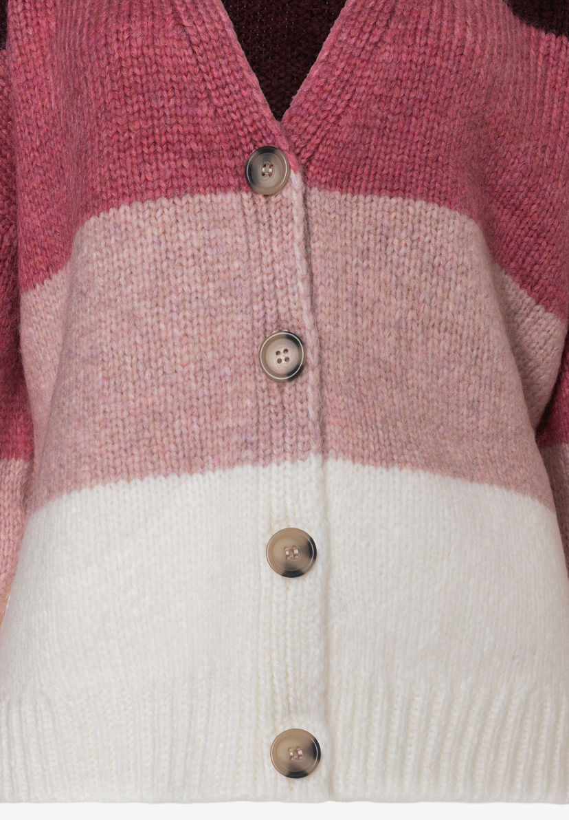 Nahaufnahme eines MORE & MORE Strick-Oberteils/Cardigans in Rosa- und Weißtönen mit Knöpfen. Nahaufnahme eines MORE & MORE Strick-Oberteils/Cardigans in Rosa- und Weißtönen mit Knöpfen.