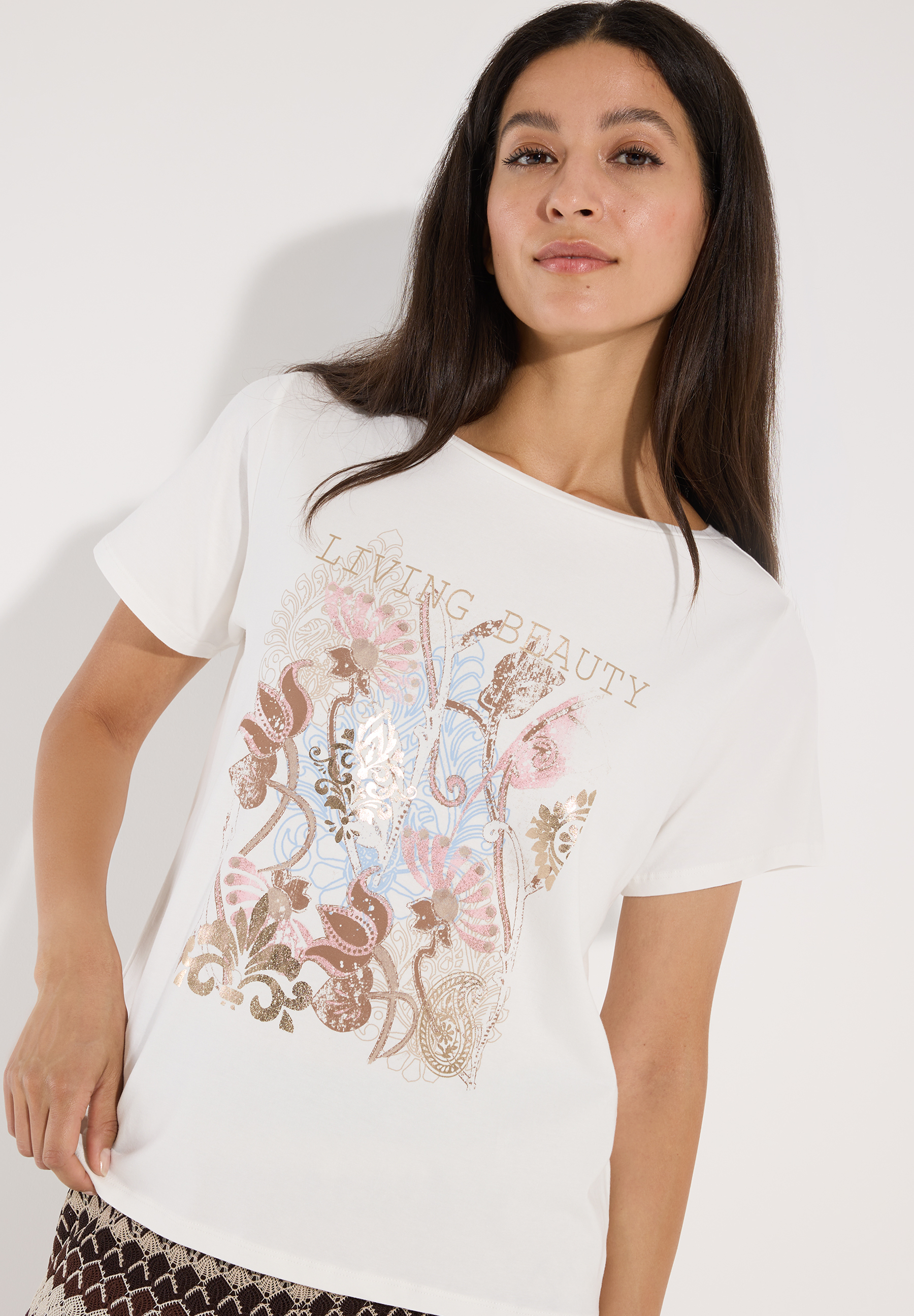 MORE & MORE Jersey-T-Shirt mit Blumendruck. Modell trägt ein weißes Oberteil mit kurzen Ärmeln und buntem Floralmuster.