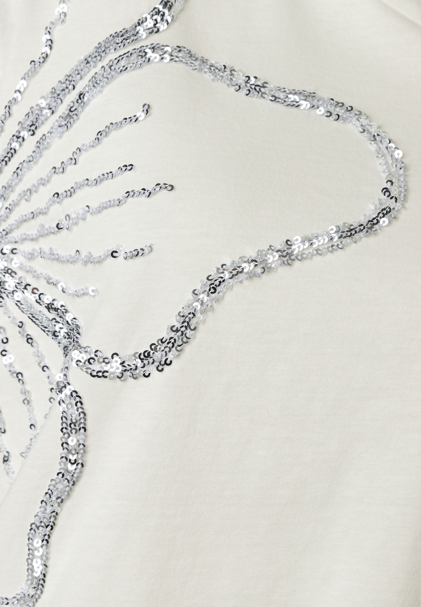 Detailaufnahme eines MORE & MORE Oberteils mit Jersey-Material und silberfarbenem Pailletten-Design.