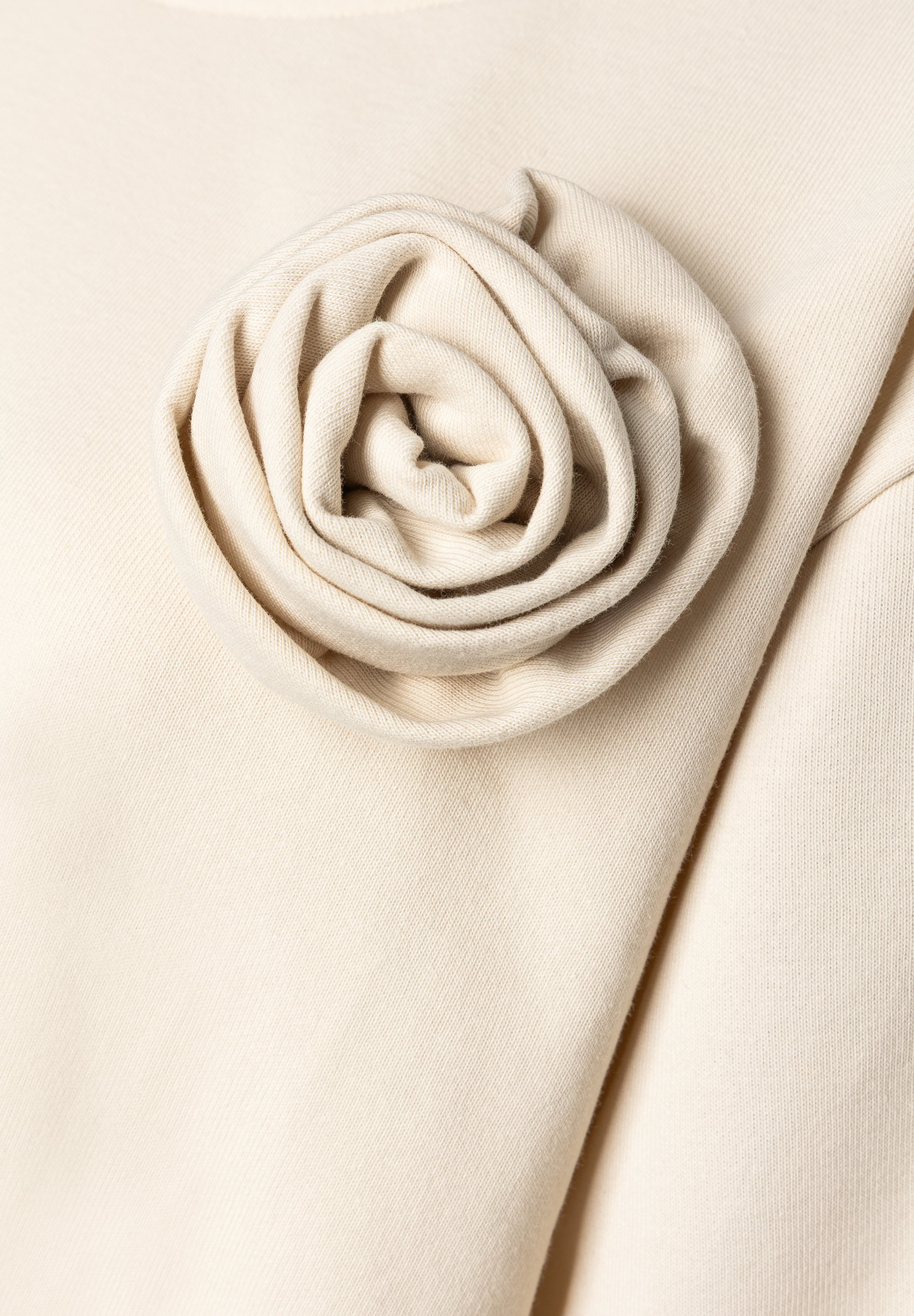 MORE & MORE Sweatshirt: Nahaufnahme der cremefarbenen Stoffblume, die oben links auf einem Oberteil drapiert ist. MORE & MORE Sweatshirt: Nahaufnahme der cremefarbenen Stoffblume, die oben links auf einem Oberteil drapiert ist.