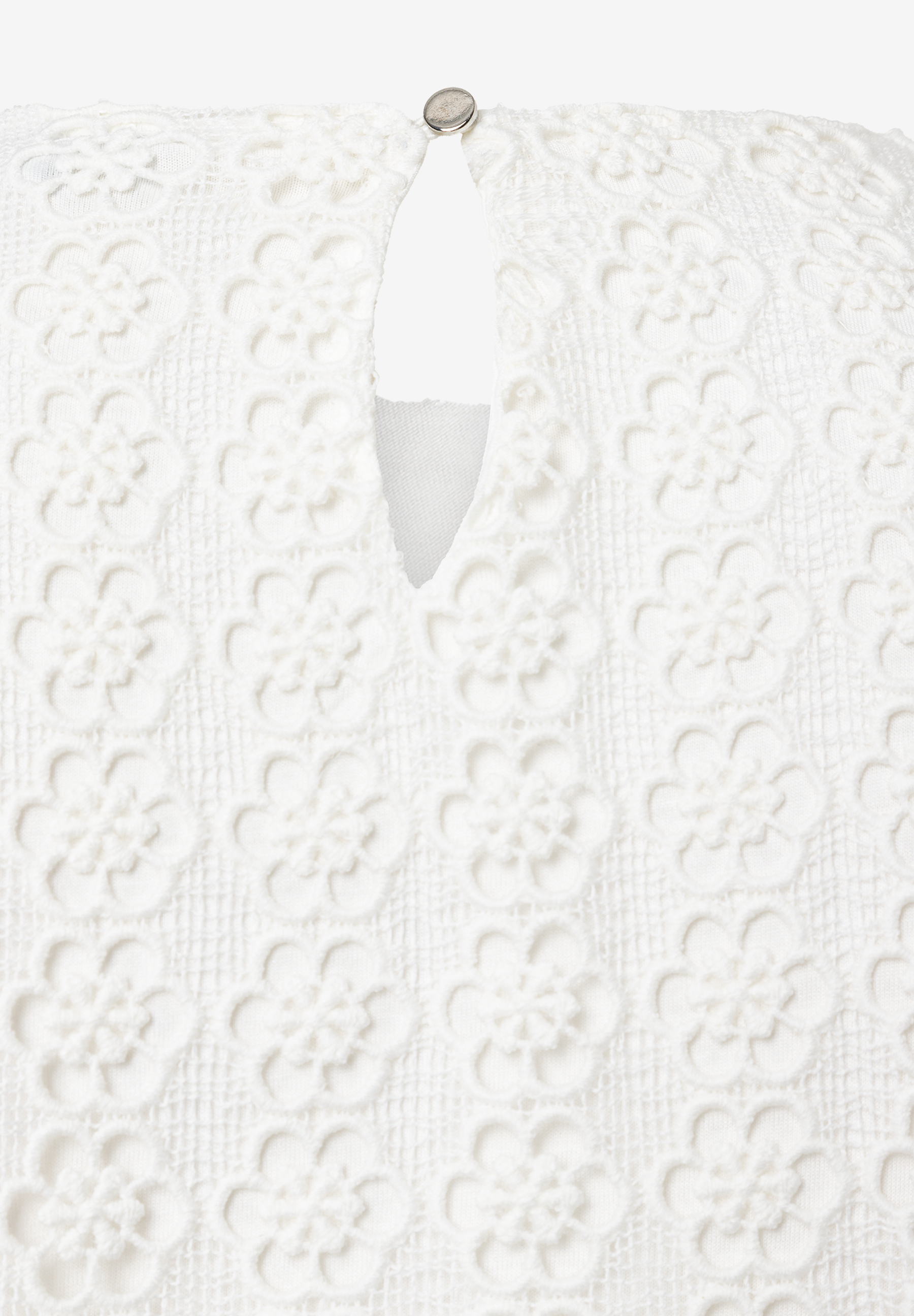 Detailaufnahme einer MORE & MORE Bluse aus angenehmer, weißer Spitze mit Knopf am runden Halsausschnitt. Detailaufnahme einer MORE & MORE Bluse aus angenehmer, weißer Spitze mit Knopf am runden Halsausschnitt.