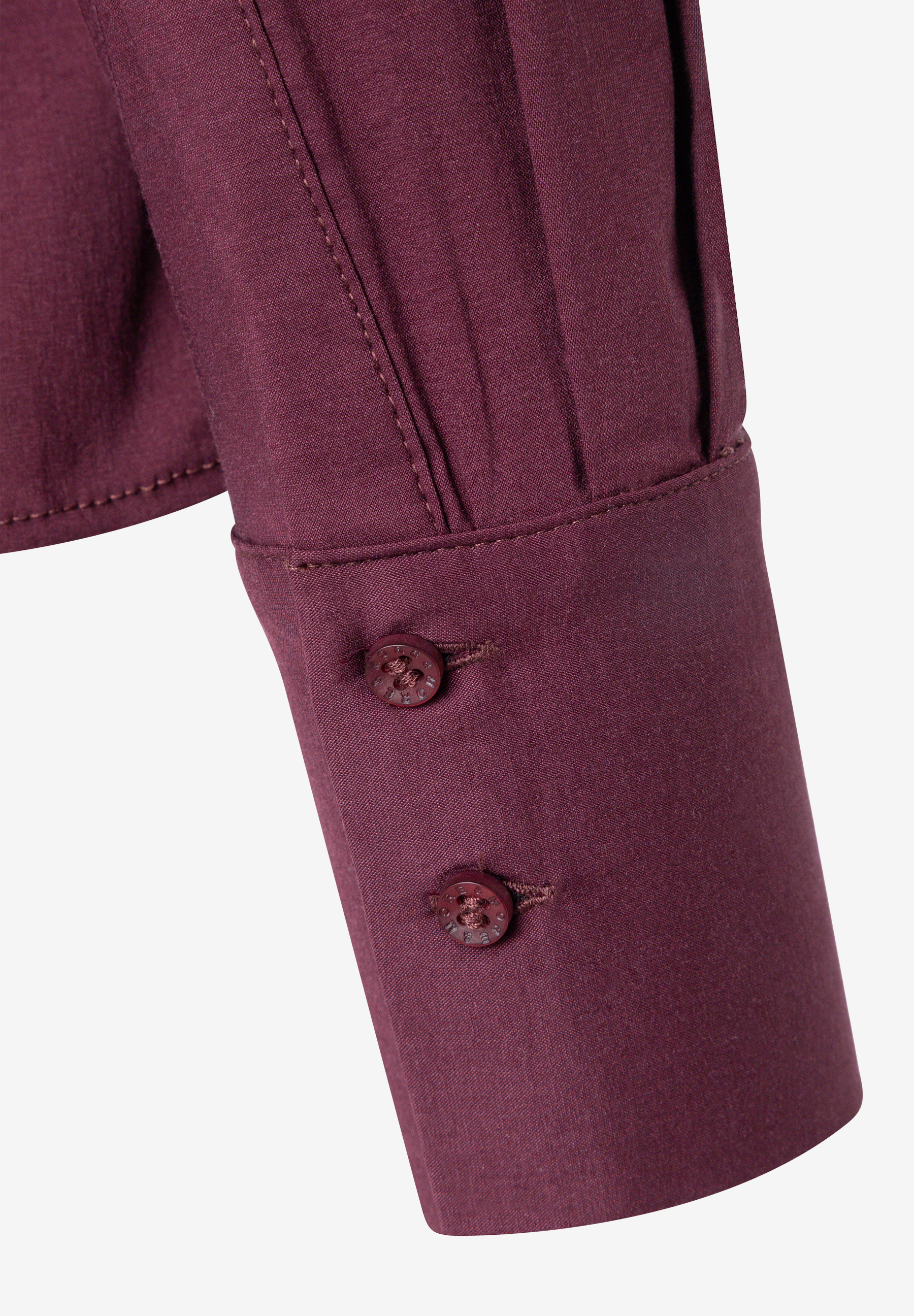 MORE & MORE Bluse, Detailansicht des Ärmels mit zwei dunkelroten Knöpfen vor weißem Hintergrund. MORE & MORE Bluse, Detailansicht des Ärmels mit zwei dunkelroten Knöpfen vor weißem Hintergrund.
