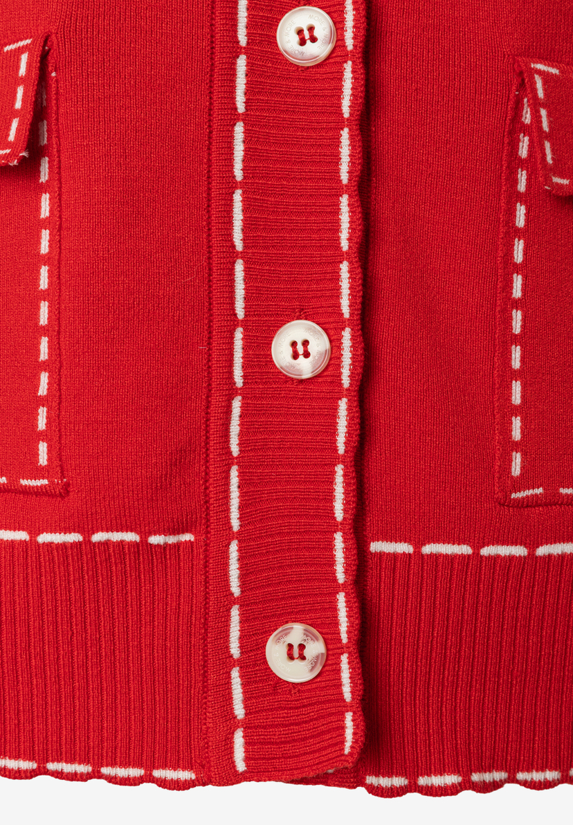 Nahaufnahme einer roten Strickjacke von MORE & MORE mit weißen Ziernähten und Knöpfen. Nahaufnahme einer roten Strickjacke von MORE & MORE mit weißen Ziernähten und Knöpfen.