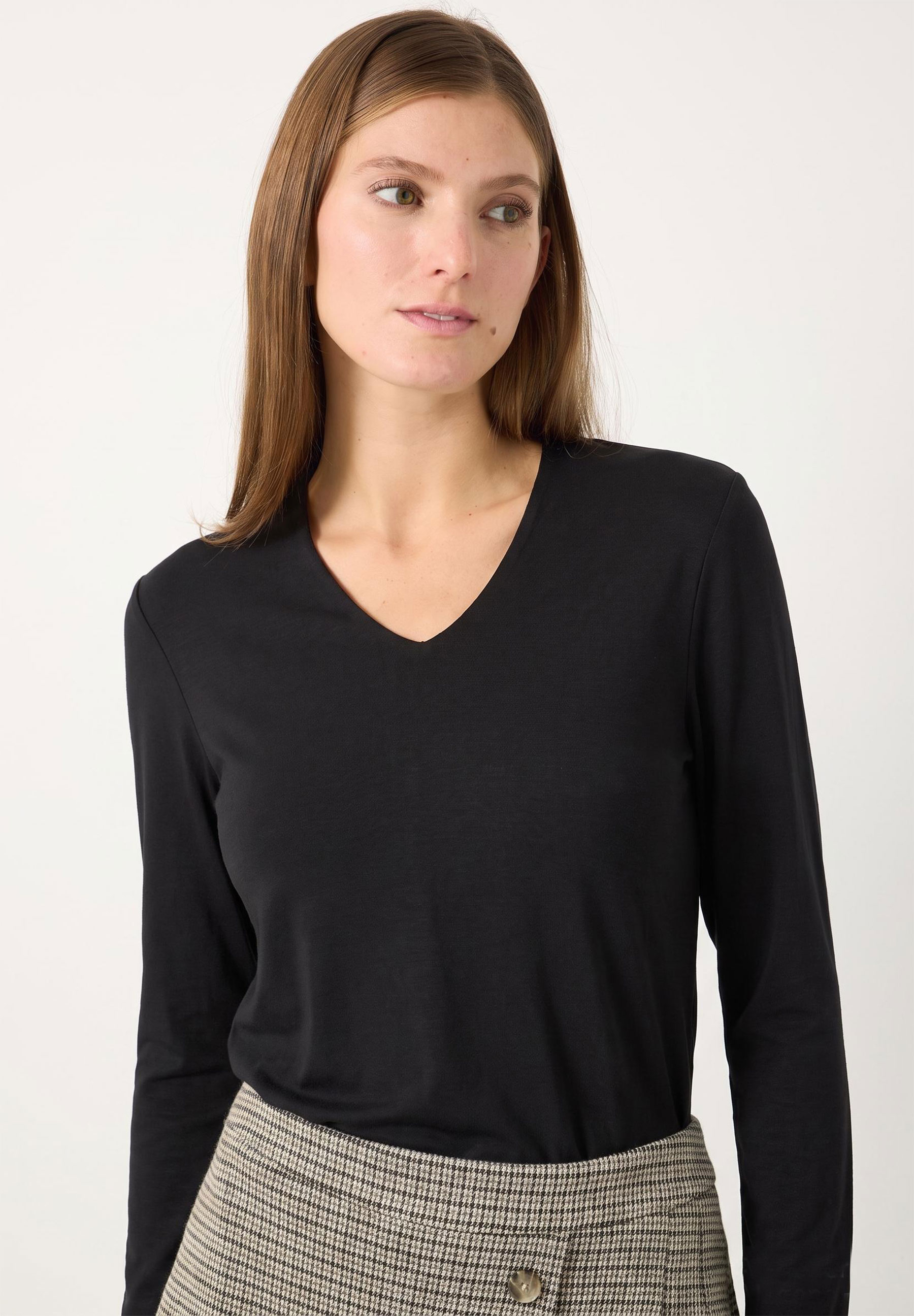 MORE & MORE schwarzes Jersey-Langarmshirt mit V-Ausschnitt, elastischem Material, kombiniert mit kariertem Rock.