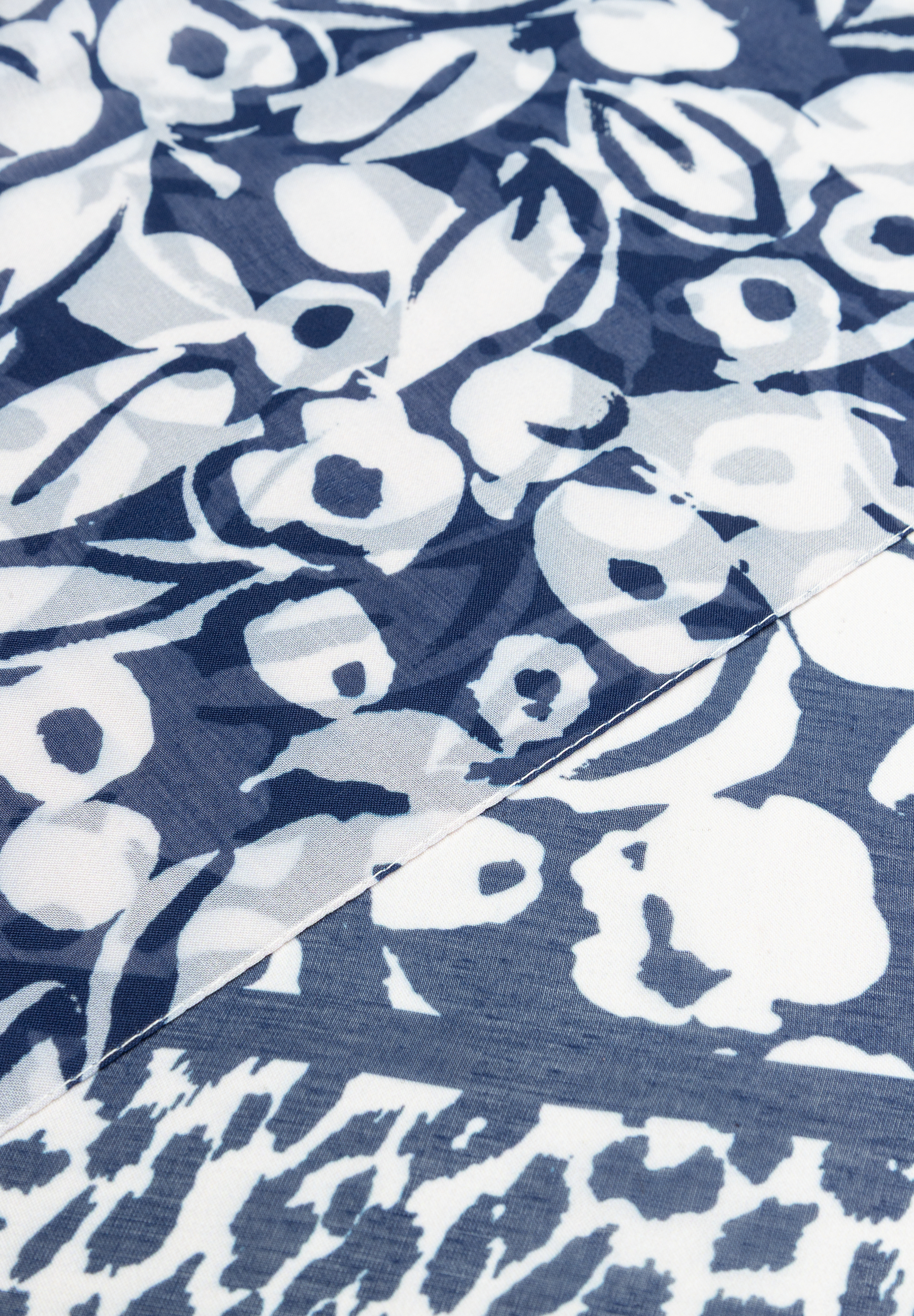 Nahaufnahme eines MORE & MORE Accessoires mit blau-weißem Blumenmuster und einer Naht. Nahaufnahme eines MORE & MORE Accessoires mit blau-weißem Blumenmuster und einer Naht.