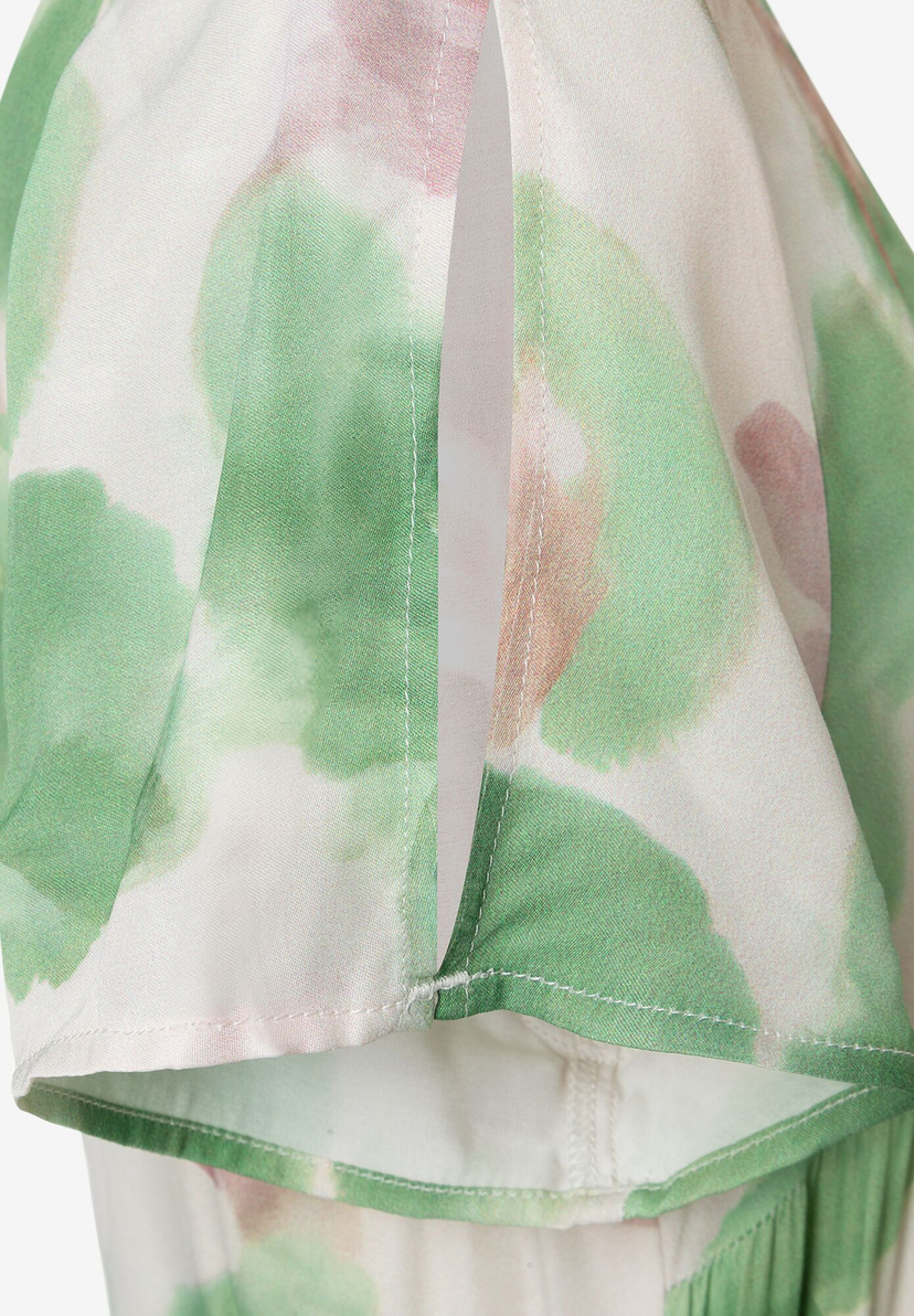 Ausschnitt eines MORE & MORE Oberteils aus Viskose-Satin mit grün-rosa Farbklecksen und weißen Nähten. Ausschnitt eines MORE & MORE Oberteils aus Viskose-Satin mit grün-rosa Farbklecksen und weißen Nähten.