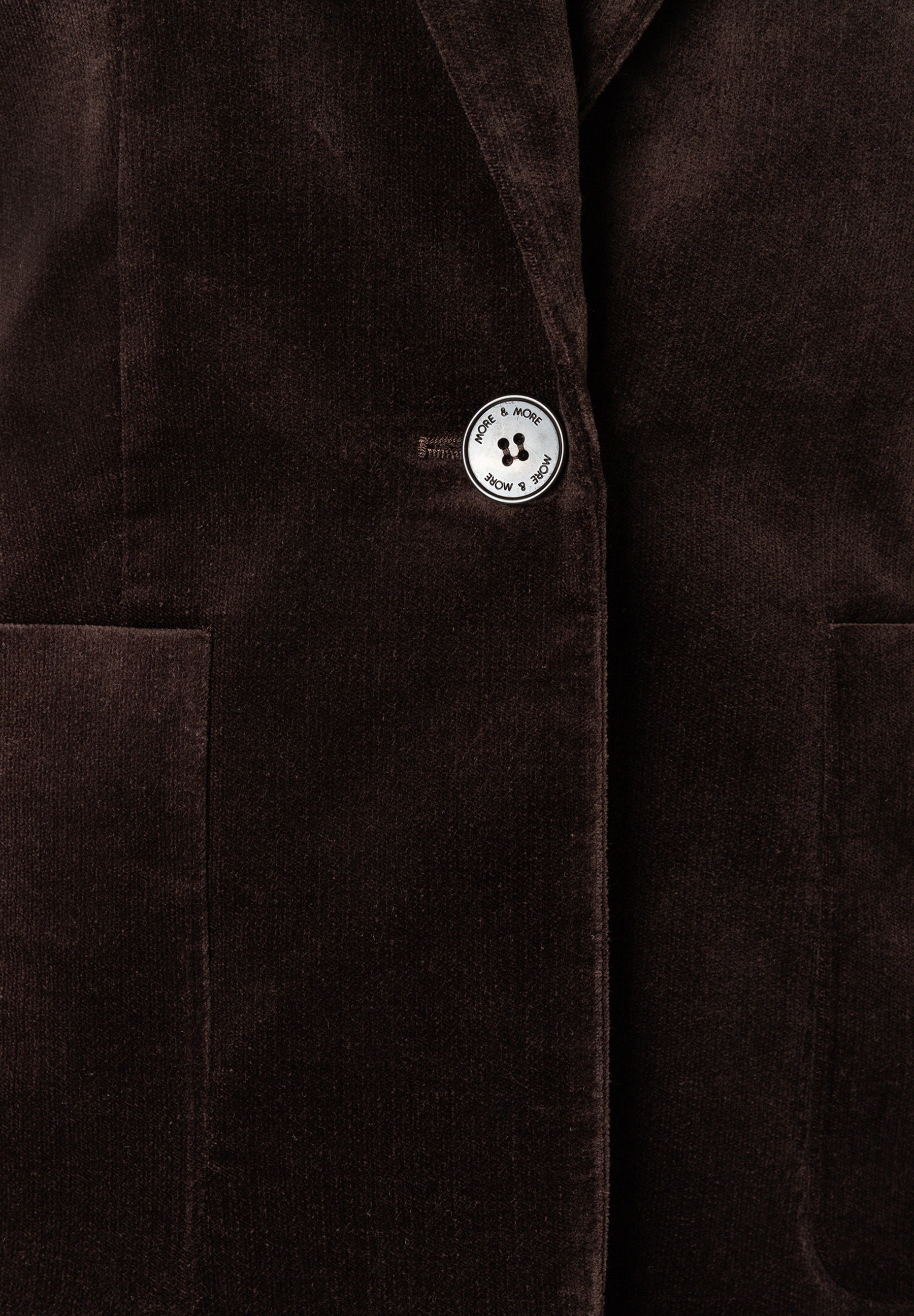 MORE & MORE Blazer in Dunkelbraun, gerippt. Nahaufnahme des Blazers mit Details zum Knopf in der Mitte der Brust. MORE & MORE Blazer in Dunkelbraun, gerippt. Nahaufnahme des Blazers mit Details zum Knopf in der Mitte der Brust.