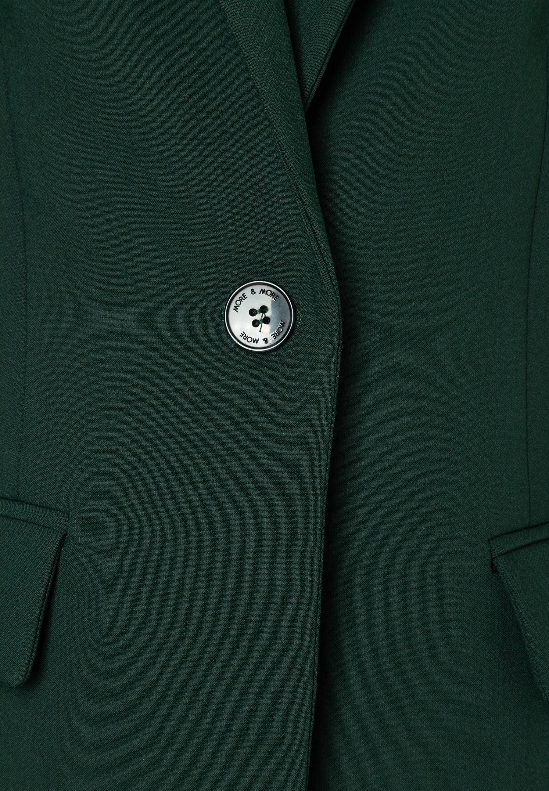 MORE & MORE Blazer in Dunkelgrün, angenehmer Tragekomfort, elastische Webware, Detail: ein einziger silberner Knopf mit Label-Prägung. MORE & MORE Blazer in Dunkelgrün, angenehmer Tragekomfort, elastische Webware, Detail: ein einziger silberner Knopf mit Label-Prägung.