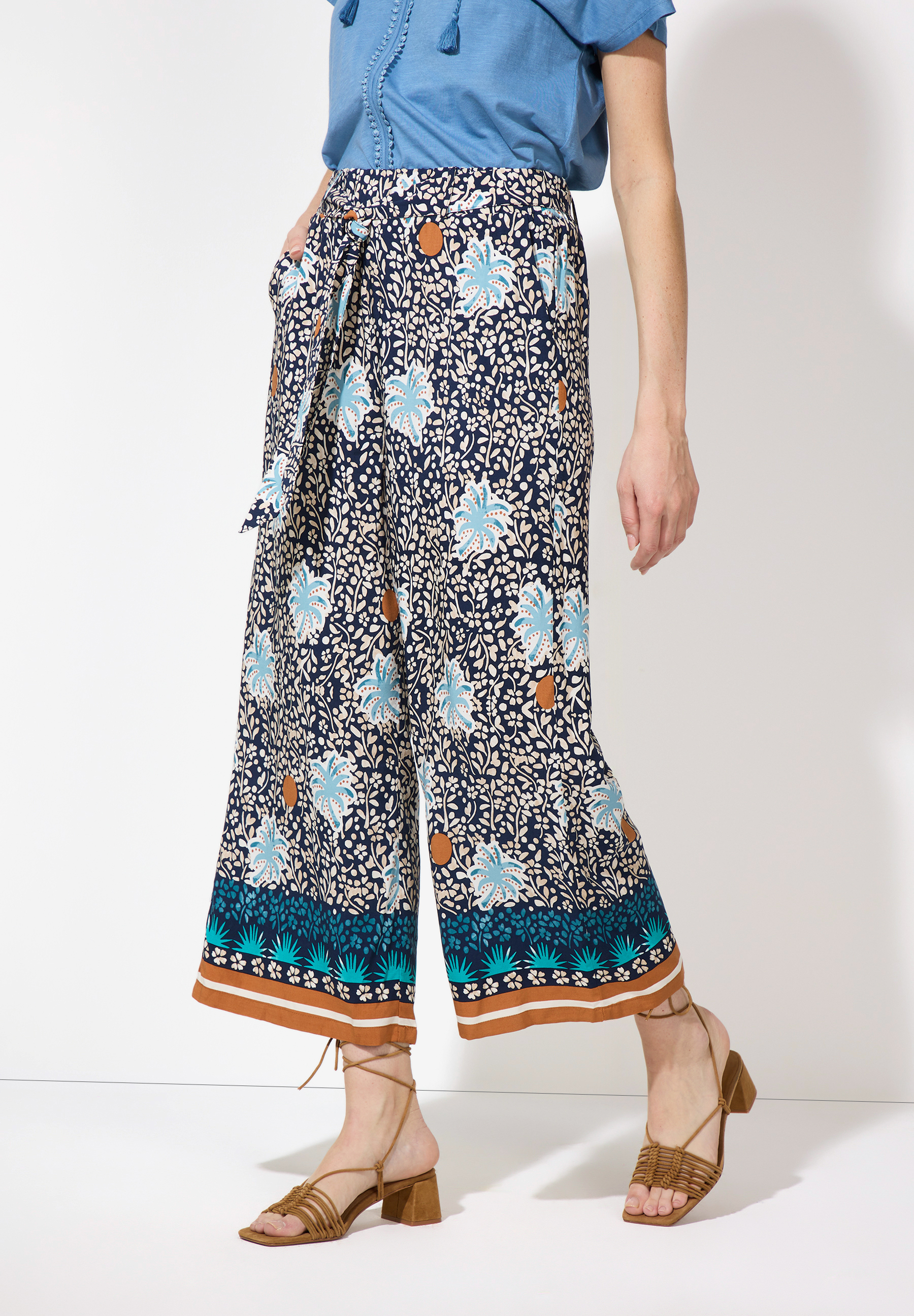 Eine Frau in MORE & MORE Hose mit Blumenmuster und Sandalen. Eine Frau in MORE & MORE Hose mit Blumenmuster und Sandalen.