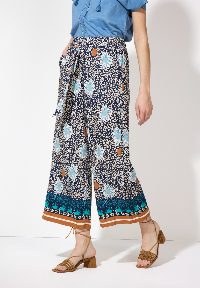 Eine Frau in MORE & MORE Hose mit Blumenmuster und Sandalen. Eine Frau in MORE & MORE Hose mit Blumenmuster und Sandalen.