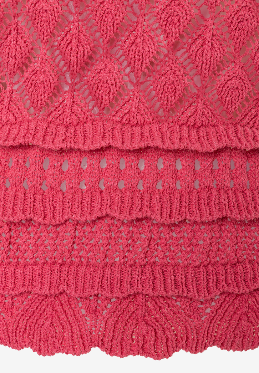 Detailansicht eines korallenroten Lochstrick-Pullovers von MORE & MORE. Das Material ist leicht transparent, elastisch und bietet Tragekomfort.