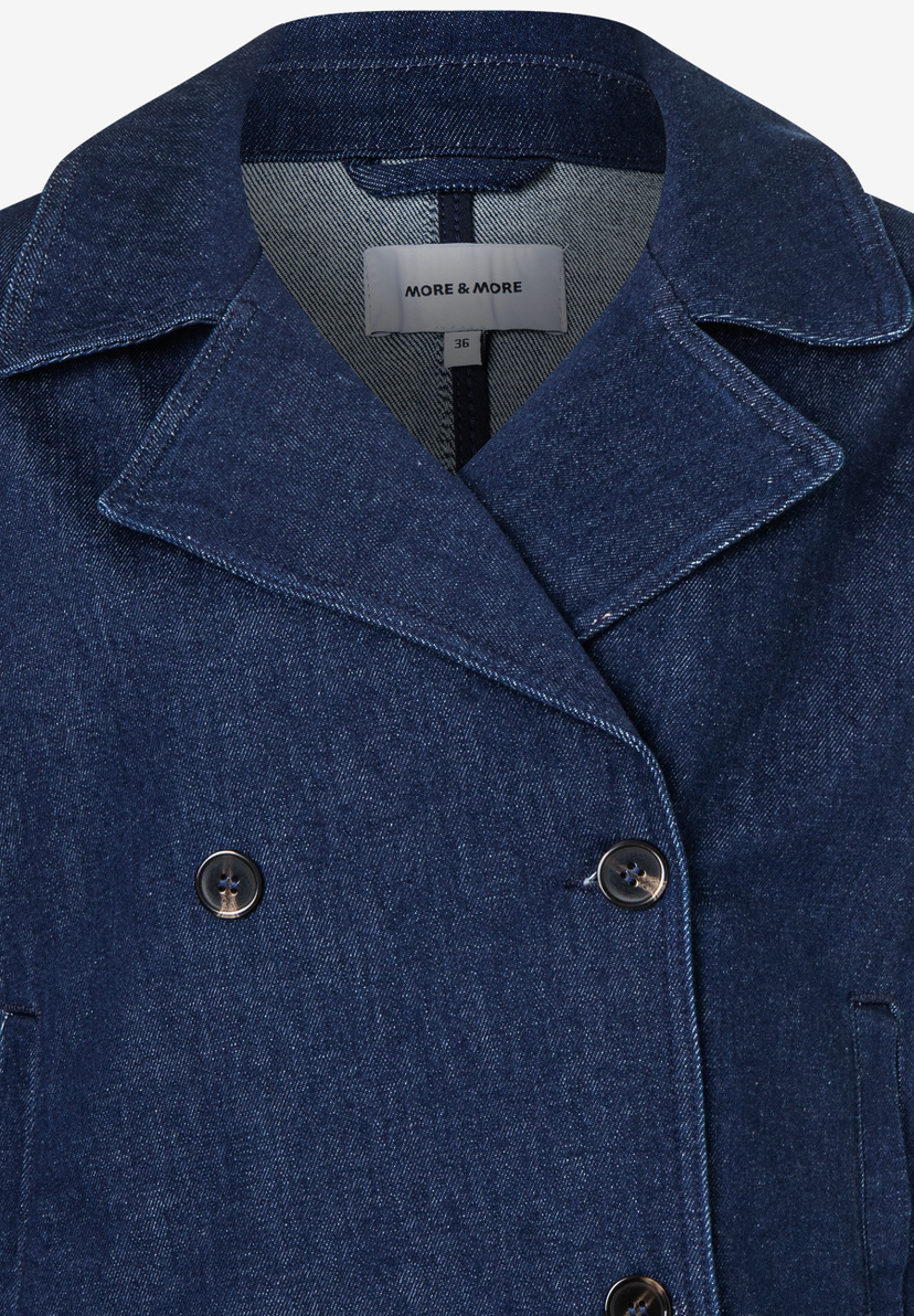 Nahaufnahme einer blauen Jeansjacke von MORE & MORE mit doppelreihiger Knopfleiste und Reverskragen. Nahaufnahme einer blauen Jeansjacke von MORE & MORE mit doppelreihiger Knopfleiste und Reverskragen.