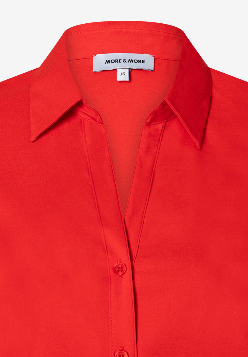 Nahaufnahme einer roten MORE & MORE Bluse aus Popeline mit Knopfleiste und Kragen. Nahaufnahme einer roten MORE & MORE Bluse aus Popeline mit Knopfleiste und Kragen.