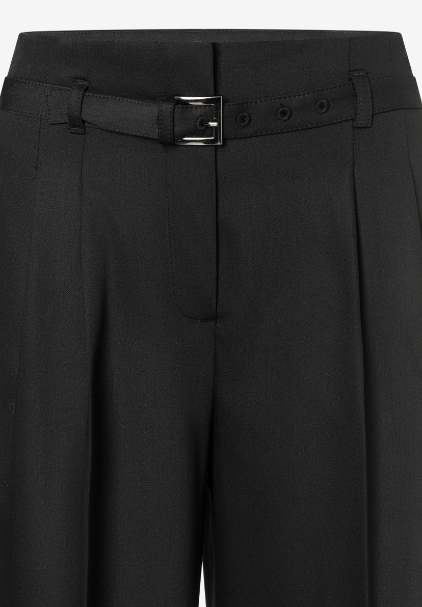 Nahaufnahme einer schwarzen MORE & MORE Hose mit Webware und Gürtel mit silberner Schnalle. Nahaufnahme einer schwarzen MORE & MORE Hose mit Webware und Gürtel mit silberner Schnalle.