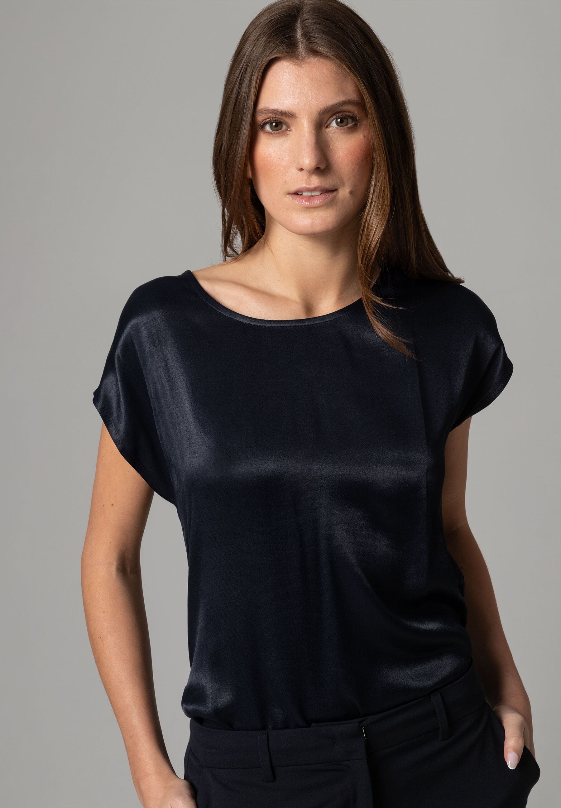 Eine Frau trägt ein schwarzes MORE & MORE Satin-Top. Schöner Glanz. Eine Frau trägt ein schwarzes MORE & MORE Satin-Top. Schöner Glanz.