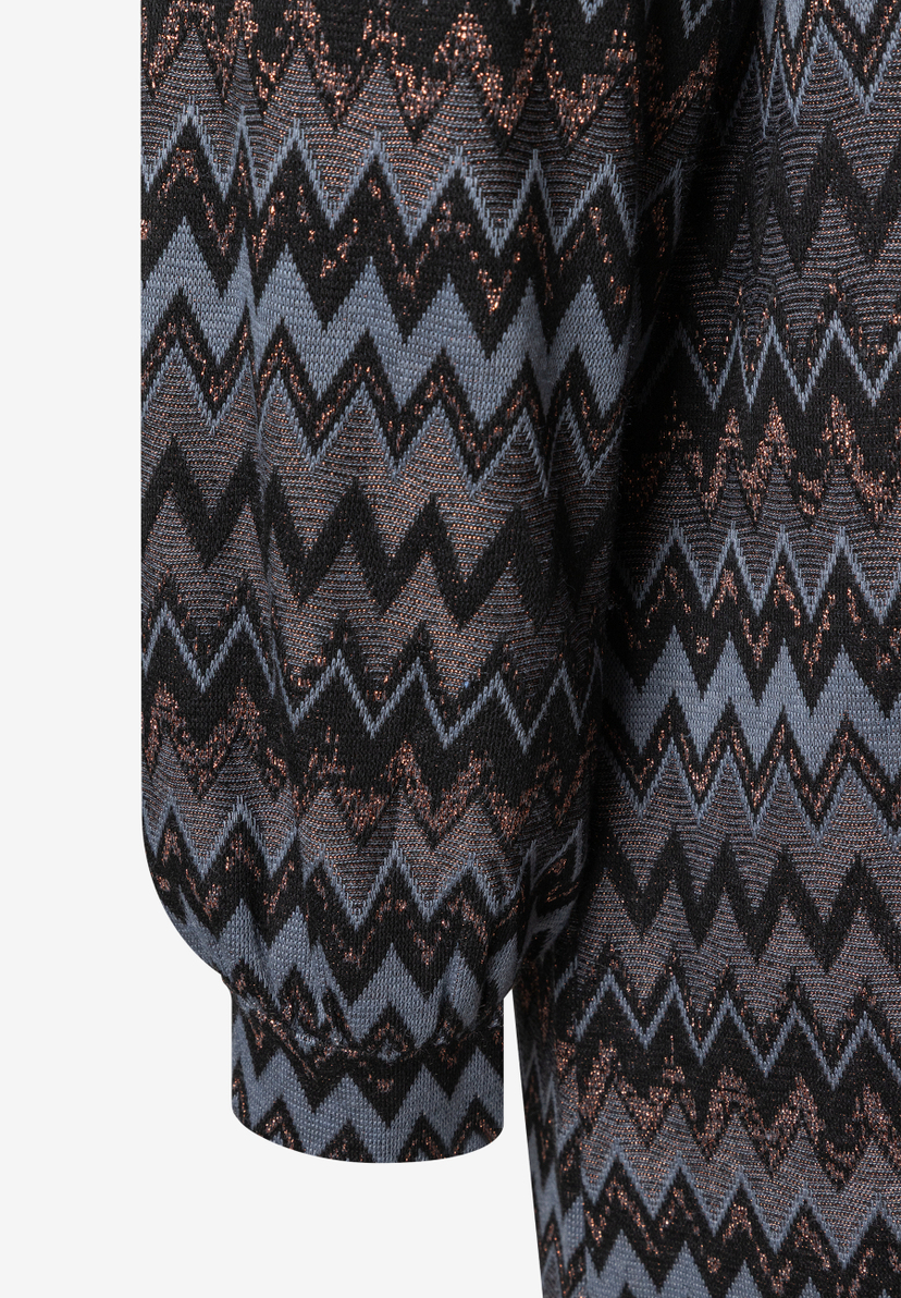 Nahaufnahme eines MORE & MORE Oberteils mit Zickzackmuster in Grau, Schwarz und Kupfer-Glitzer. Nahaufnahme eines MORE & MORE Oberteils mit Zickzackmuster in Grau, Schwarz und Kupfer-Glitzer.