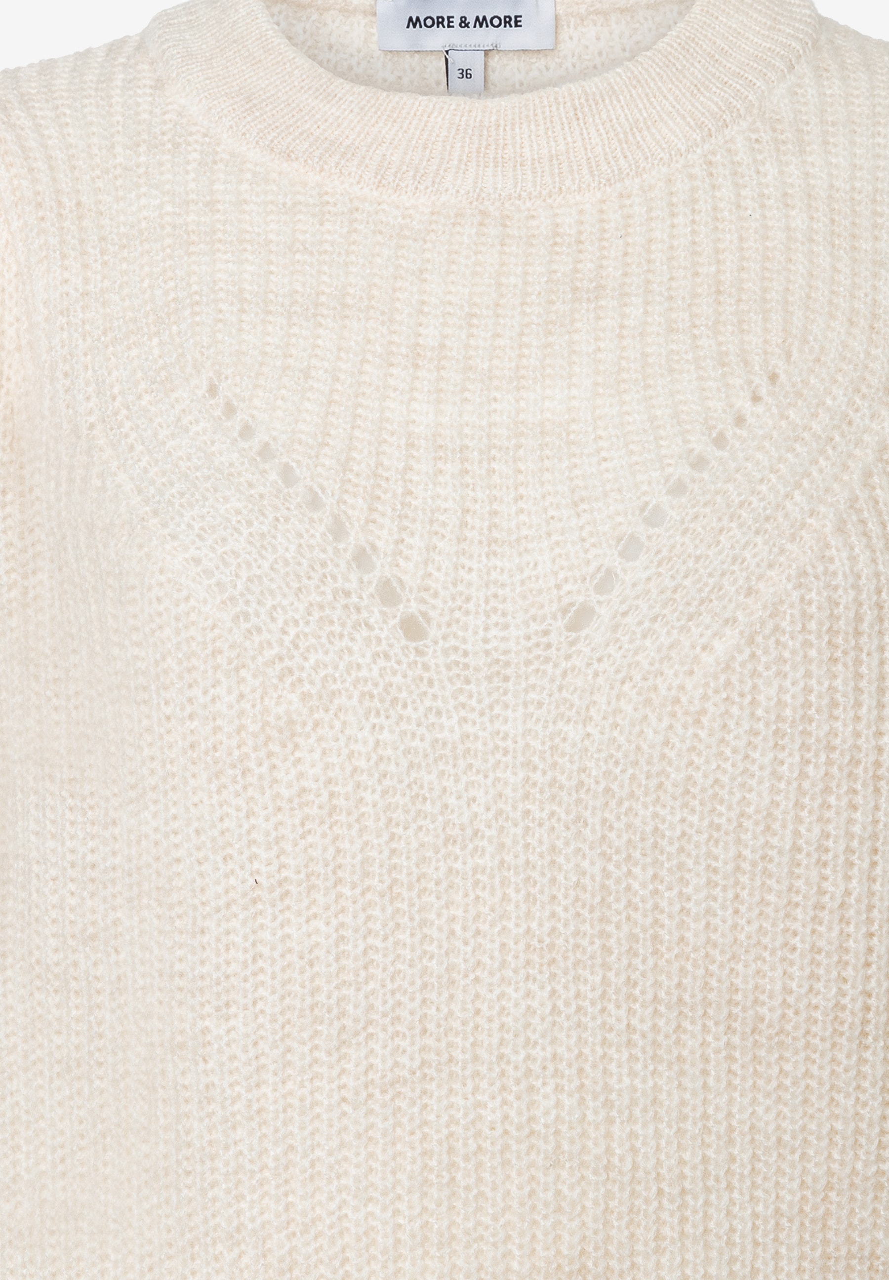 Nahaufnahme eines weißen MORE & MORE Strickpullovers mit rundem Halsausschnitt und Lochmuster. Nahaufnahme eines weißen MORE & MORE Strickpullovers mit rundem Halsausschnitt und Lochmuster.