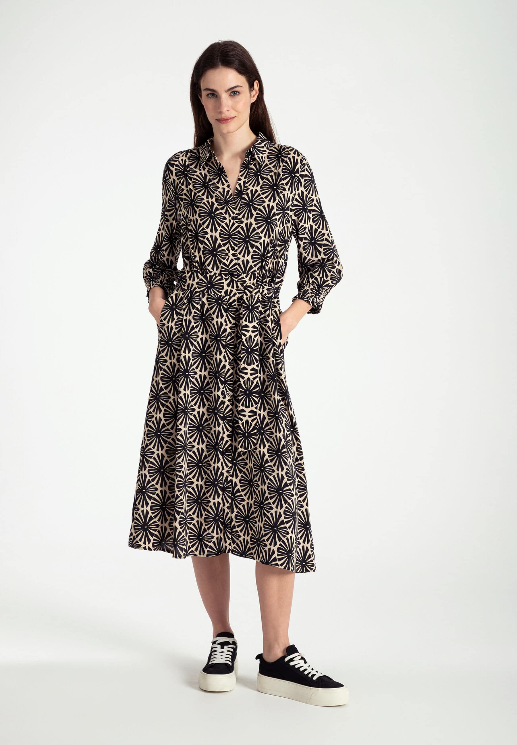 Eine Frau trägt ein Kleid von MORE & MORE mit fließender Viskose-Konstruktion. Das Oberteil hat ein schwarzes Blumenmuster.