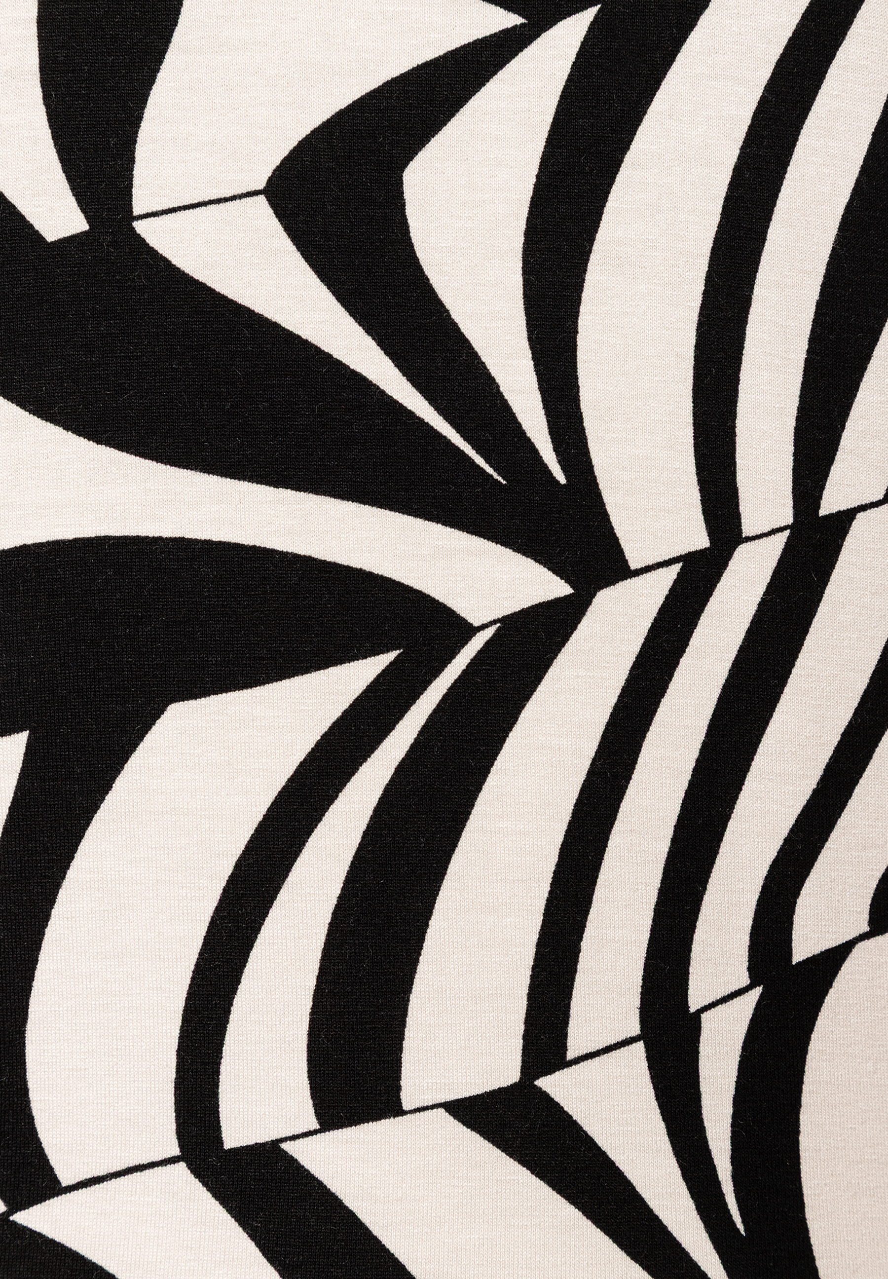 Detailaufnahme eines MORE & MORE Oberteils. Das Jersey-Material zeigt ein abstraktes, schwarz-weißes Muster. Detailaufnahme eines MORE & MORE Oberteils. Das Jersey-Material zeigt ein abstraktes, schwarz-weißes Muster.