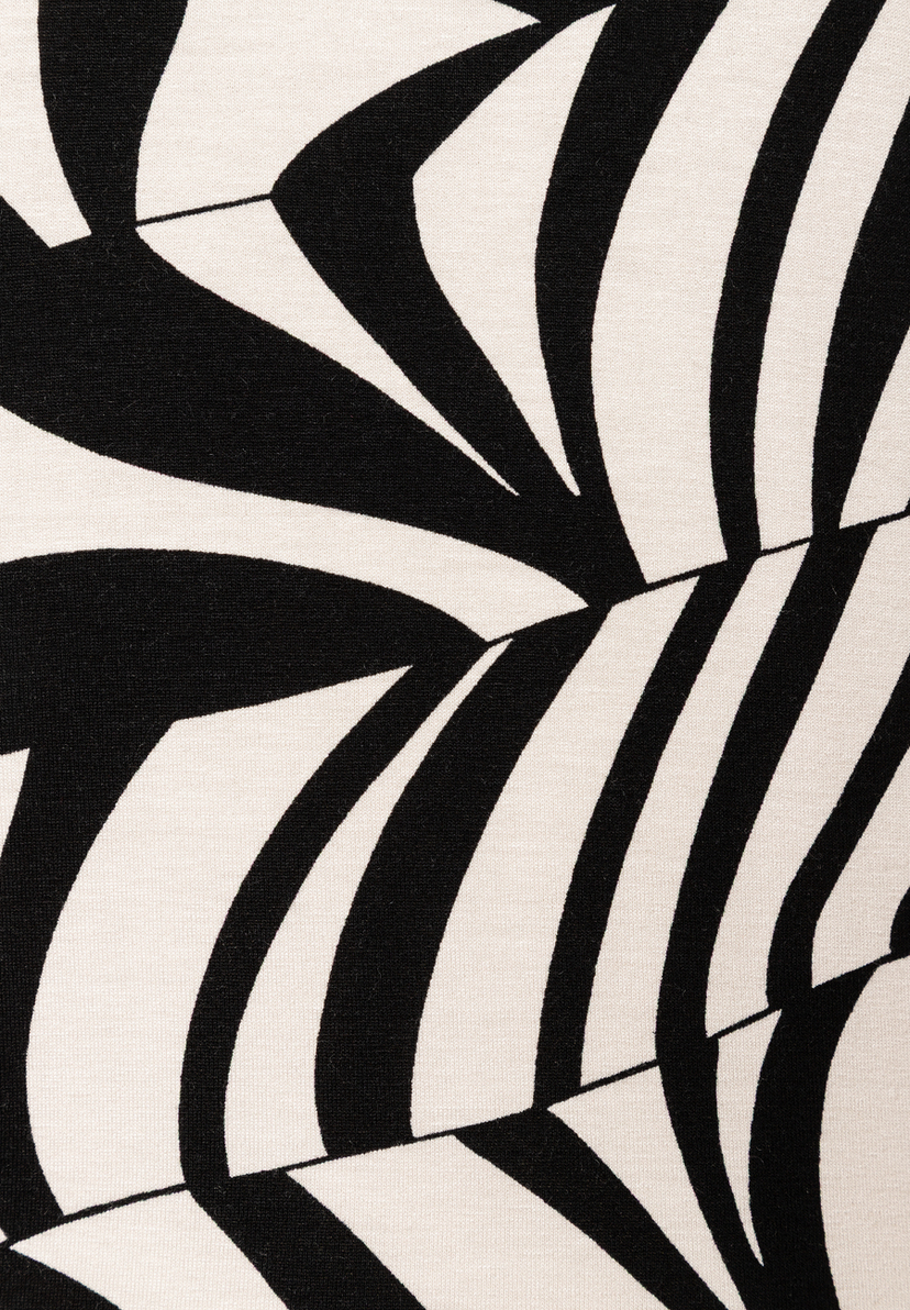 Detailaufnahme eines MORE & MORE Oberteils. Das Jersey-Material zeigt ein abstraktes, schwarz-weißes Muster. Detailaufnahme eines MORE & MORE Oberteils. Das Jersey-Material zeigt ein abstraktes, schwarz-weißes Muster.