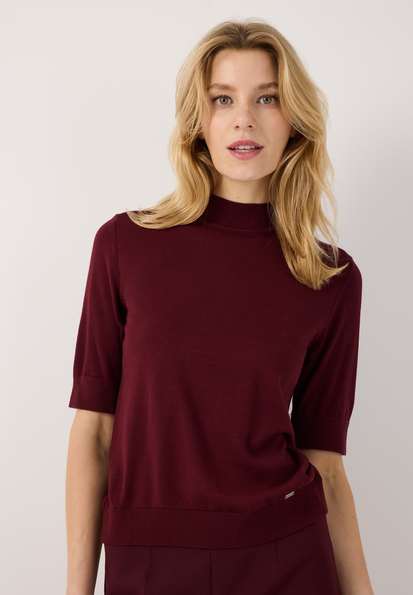 MORE & MORE Feinstrick-Pullover in Schwarz. Das Model trägt ein figurbetontes Oberteil mit kurzen Ärmeln und Stehkragen. MORE & MORE Feinstrick-Pullover in Schwarz. Das Model trägt ein figurbetontes Oberteil mit kurzen Ärmeln und Stehkragen.