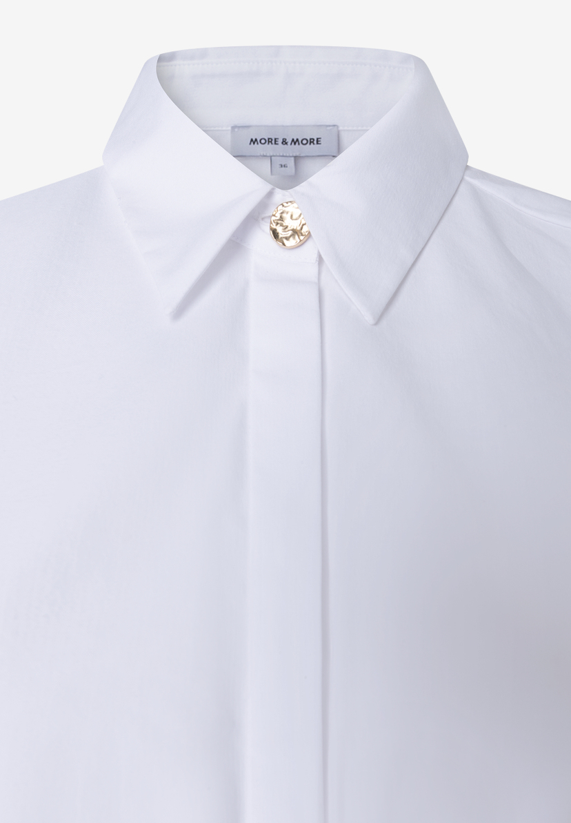 MORE & MORE weiße Bluse. Detailaufnahme zeigt goldenen, runden Knopfverschluss, der wie gehämmert aussieht. MORE & MORE weiße Bluse. Detailaufnahme zeigt goldenen, runden Knopfverschluss, der wie gehämmert aussieht.