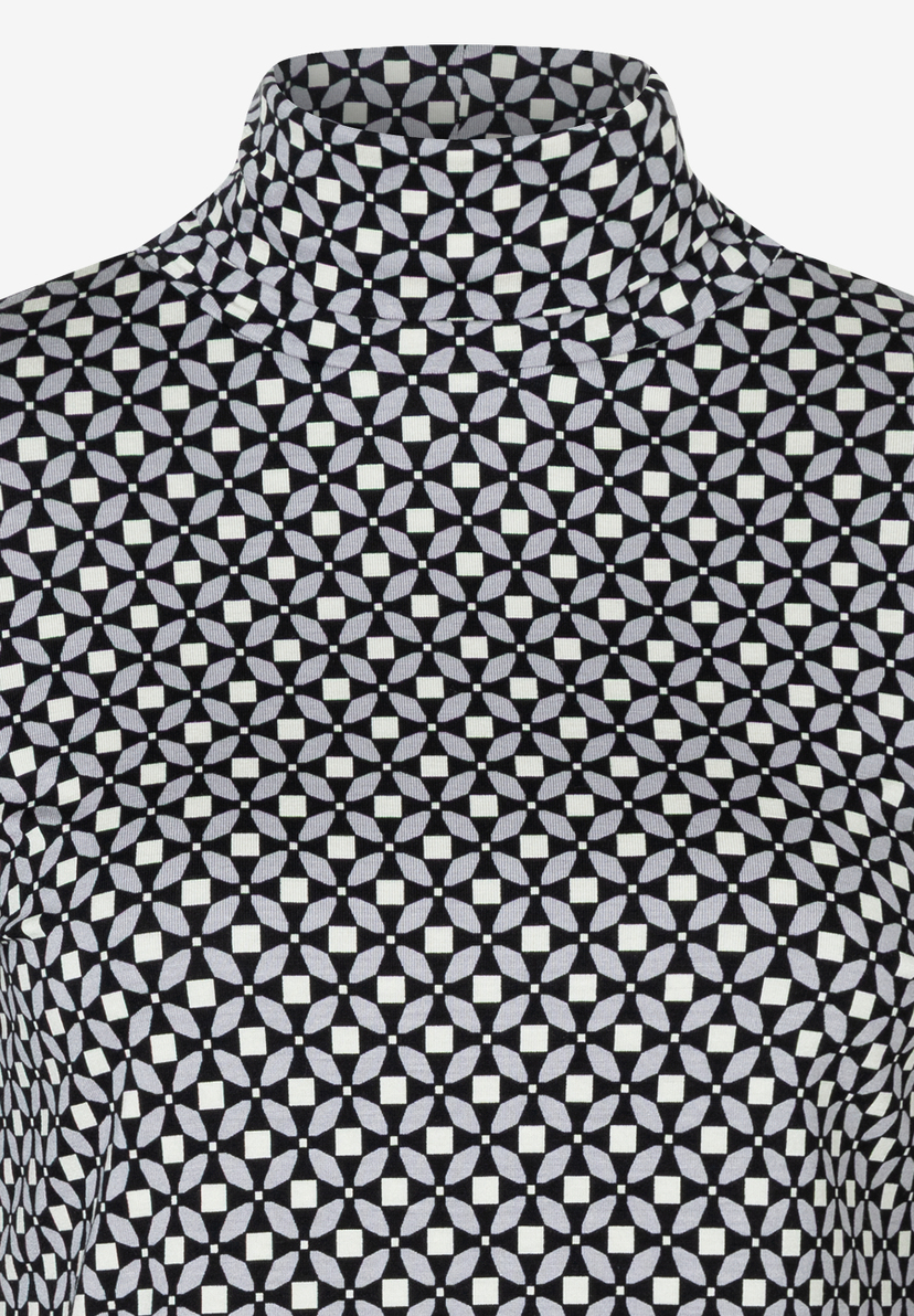 Nahaufnahme eines MORE & MORE Oberteils mit Rollkragen und geometrischem Muster. Nahaufnahme eines MORE & MORE Oberteils mit Rollkragen und geometrischem Muster.