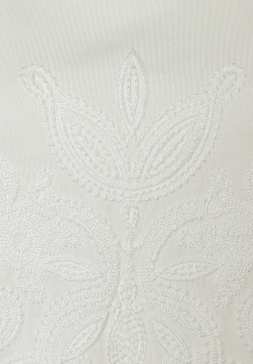 Nahaufnahme eines weißen MORE & MORE Oberteils mit Jersey-Stickerei.