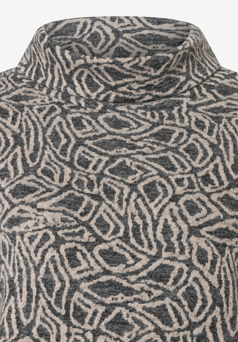 Nahaufnahme eines MORE & MORE Oberteils mit Rollkragen und abstraktem Muster. Nahaufnahme eines MORE & MORE Oberteils mit Rollkragen und abstraktem Muster.
