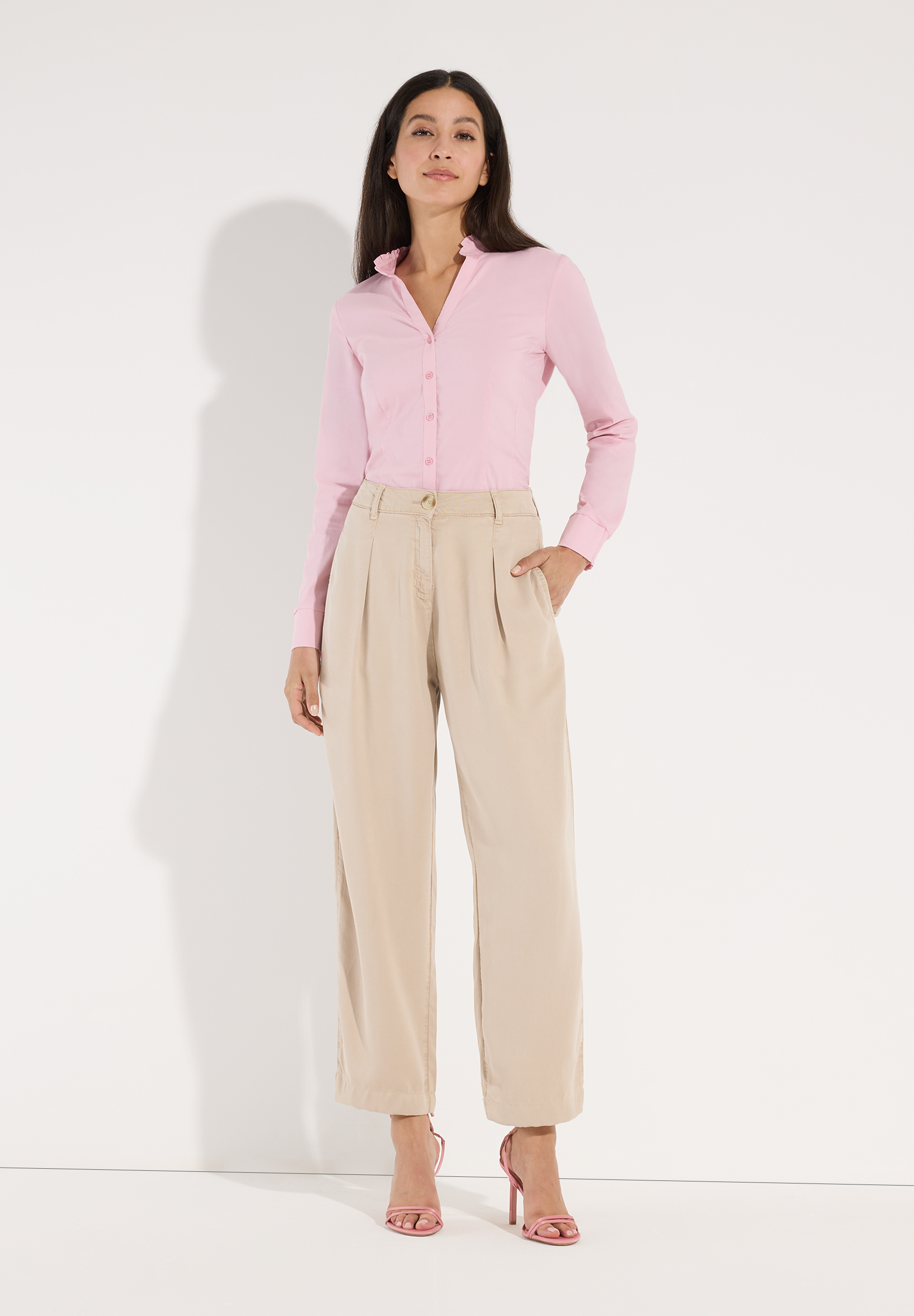 MORE & MORE Jeans: junge Frau mit lachsfarbener Hemdbluse u. beigefarbener Webware-Hose mit weitem Bein. Hände in Hosentaschen, dazu pinke Sandaletten. MORE & MORE Jeans: junge Frau mit lachsfarbener Hemdbluse u. beigefarbener Webware-Hose mit weitem Bein. Hände in Hosentaschen, dazu pinke Sandaletten.