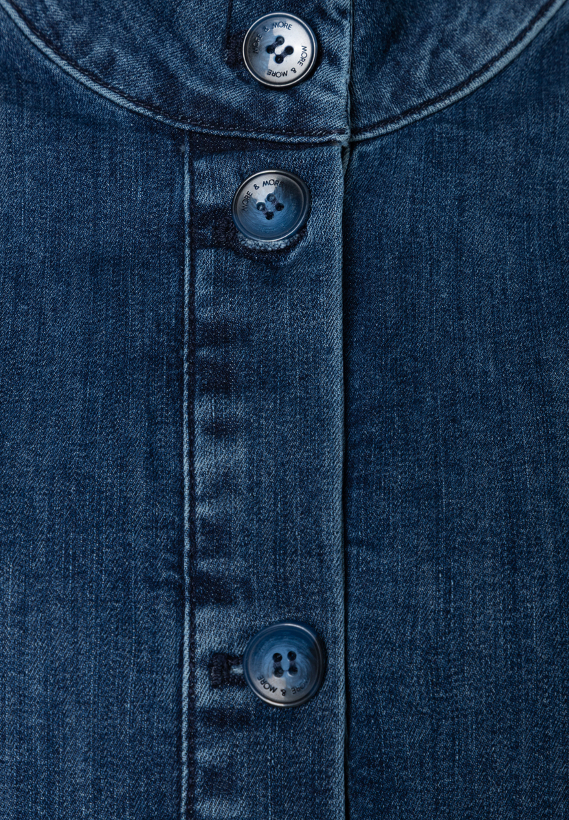 Nahaufnahme eines blauen MORE & MORE Oberteils aus Denim mit Knöpfen. Nahaufnahme eines blauen MORE & MORE Oberteils aus Denim mit Knöpfen.
