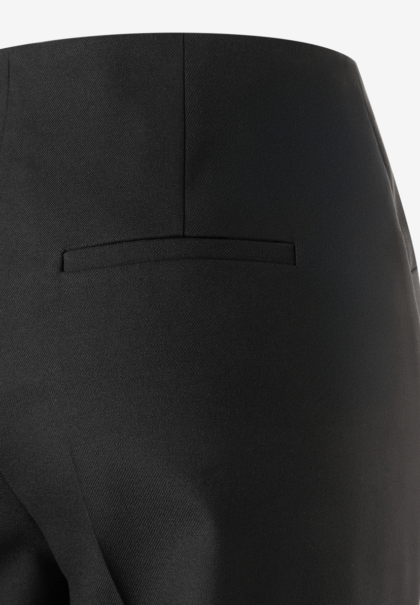 Detailaufnahme der MORE & MORE Hose. Das schwarze, fließende Gewebe zeigt eine angedeutete Gesäßtasche. Detailaufnahme der MORE & MORE Hose. Das schwarze, fließende Gewebe zeigt eine angedeutete Gesäßtasche.