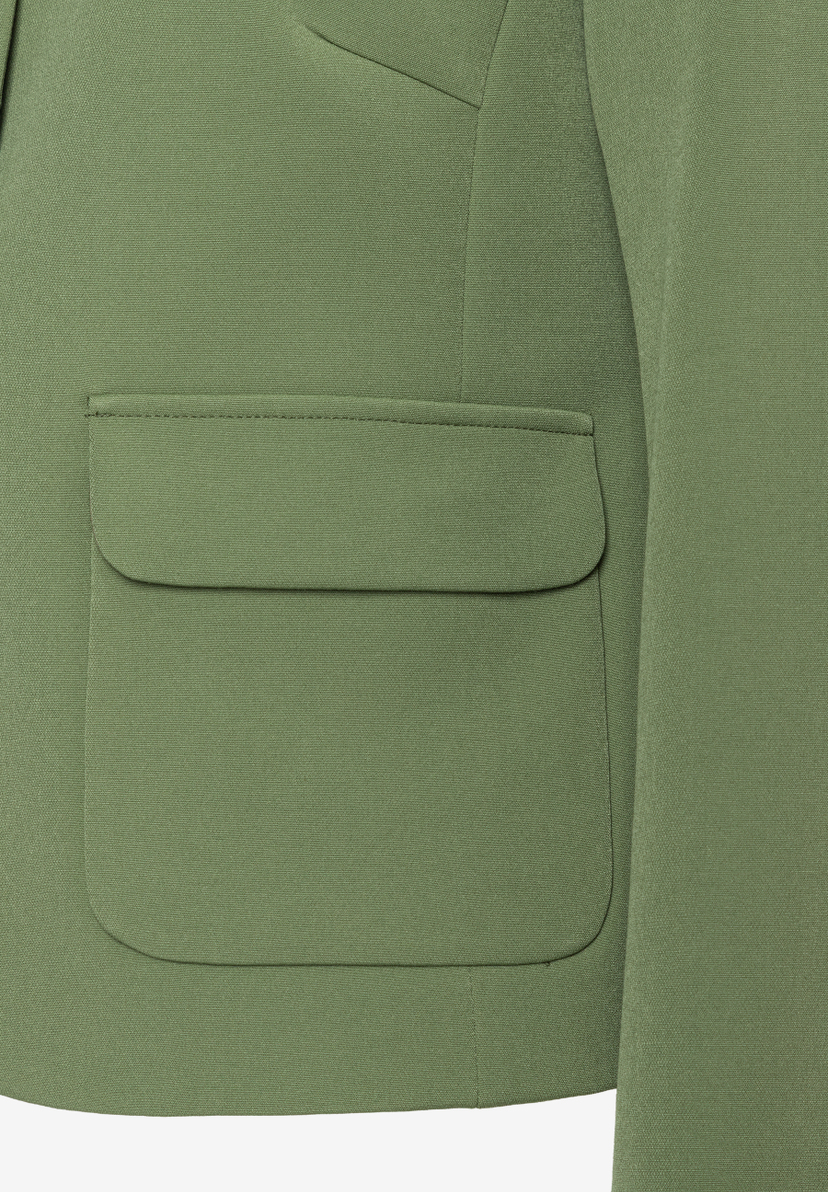 Nahaufnahme eines grünen Blazers von MORE & MORE mit aufgesetzter Tasche. Nahaufnahme eines grünen Blazers von MORE & MORE mit aufgesetzter Tasche.