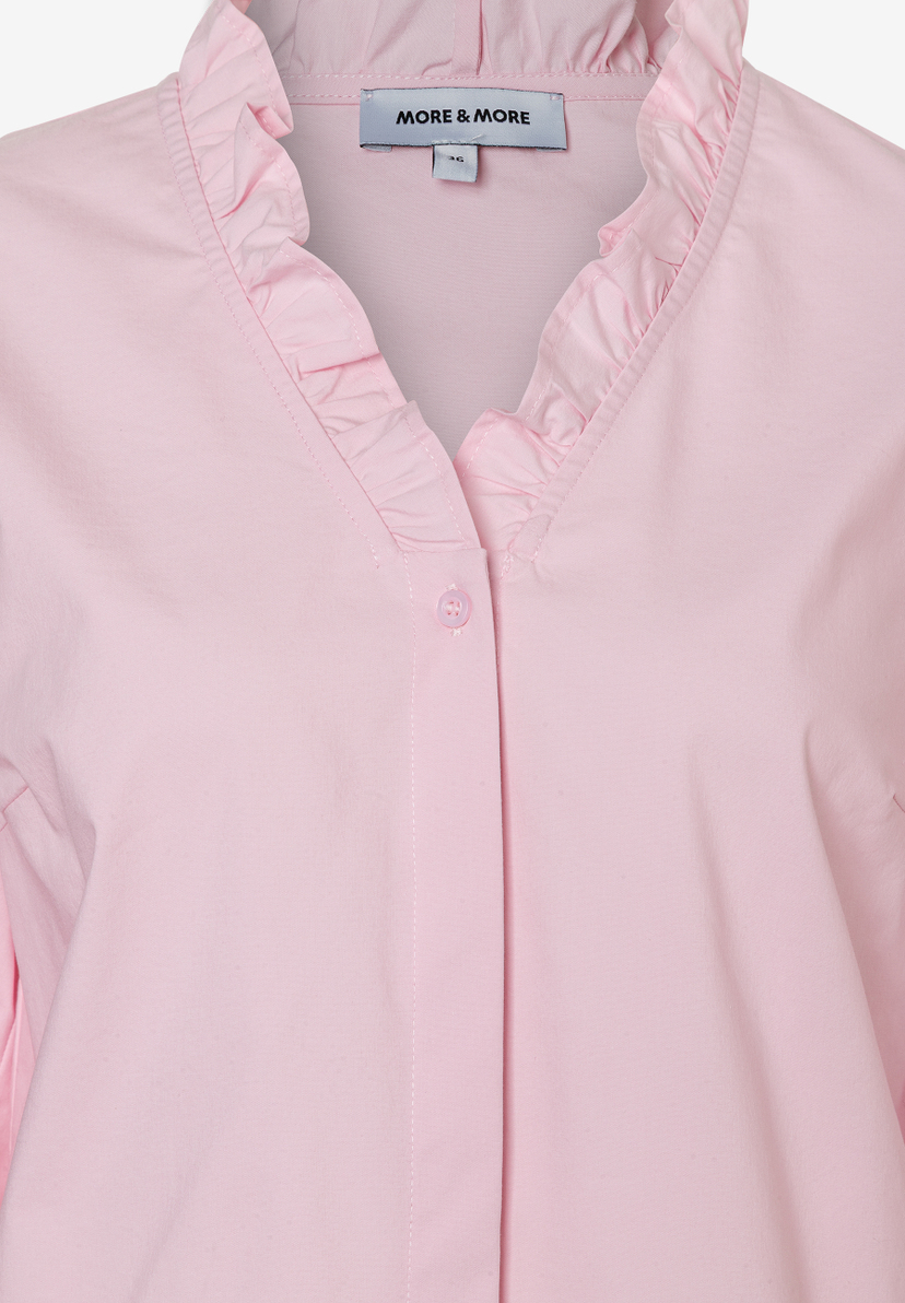Nahaufnahme einer rosa Bluse von MORE & MORE mit Rüschen am Kragen. Nahaufnahme einer rosa Bluse von MORE & MORE mit Rüschen am Kragen.