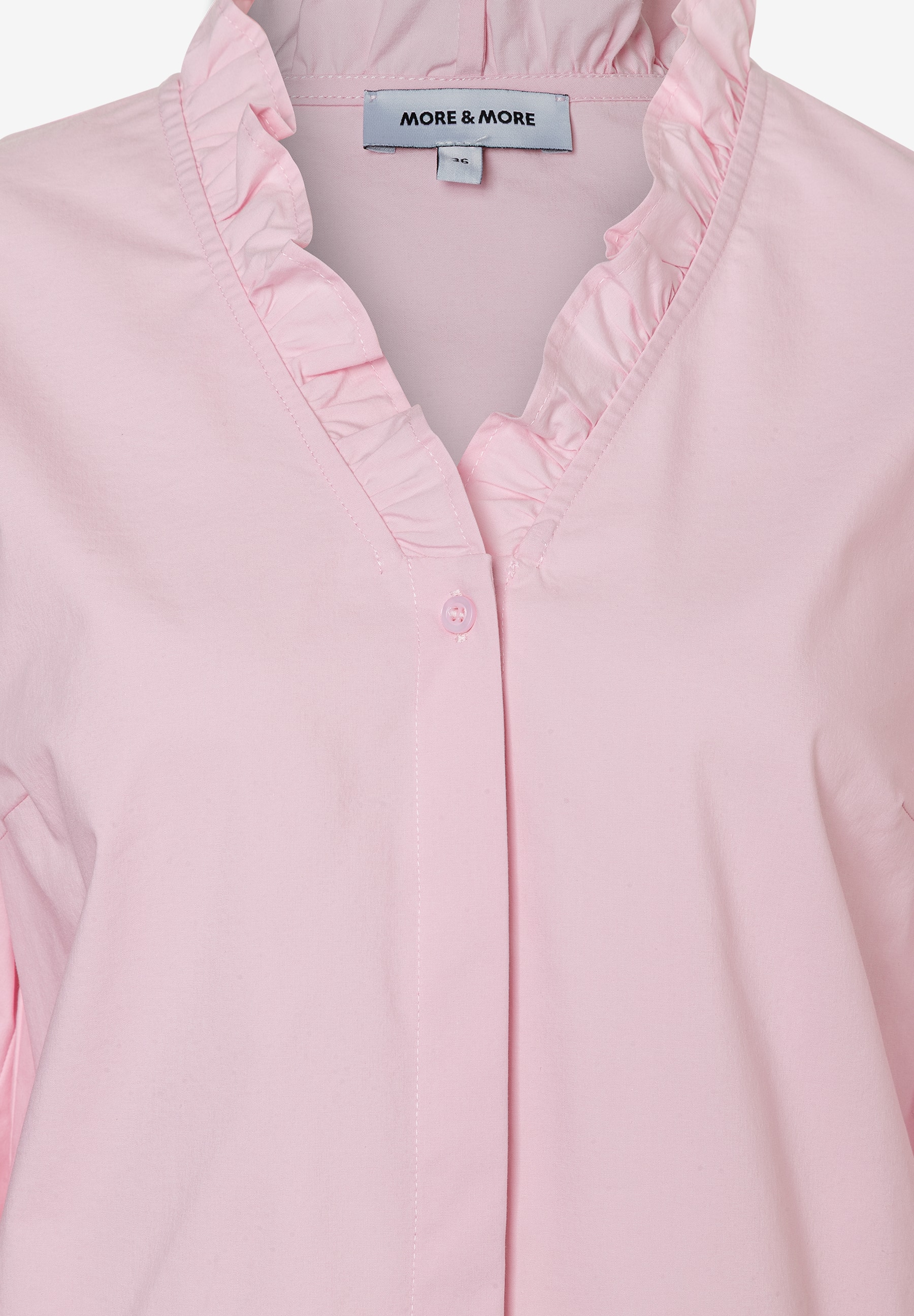 Nahaufnahme einer rosa Bluse von MORE & MORE mit Rüschen am Kragen. Nahaufnahme einer rosa Bluse von MORE & MORE mit Rüschen am Kragen.