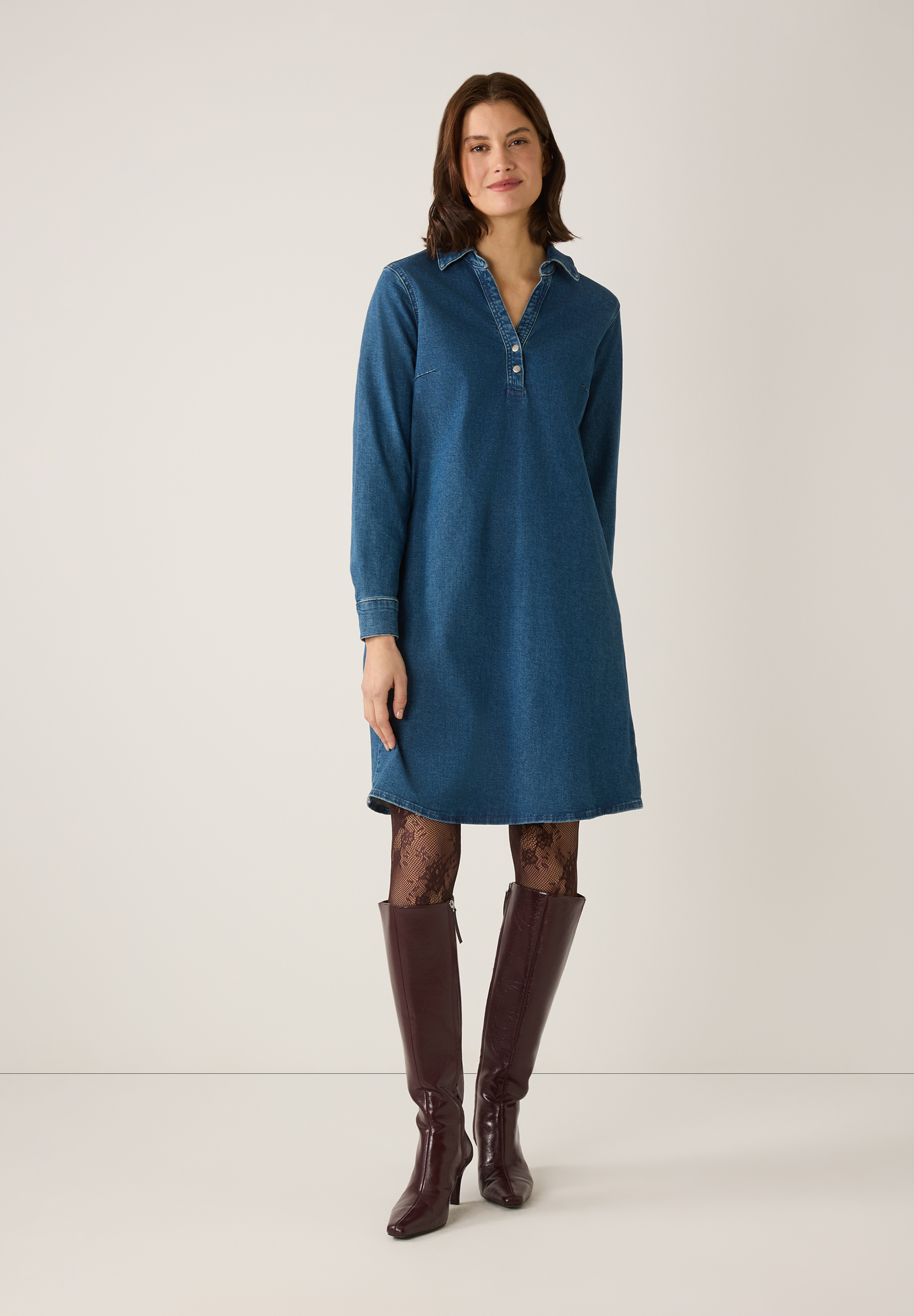 Eine Frau in einem MORE & MORE Oberteil aus Denim, blickdichter Strumpfhose und Stiefeln. Eine Frau in einem MORE & MORE Oberteil aus Denim, blickdichter Strumpfhose und Stiefeln.