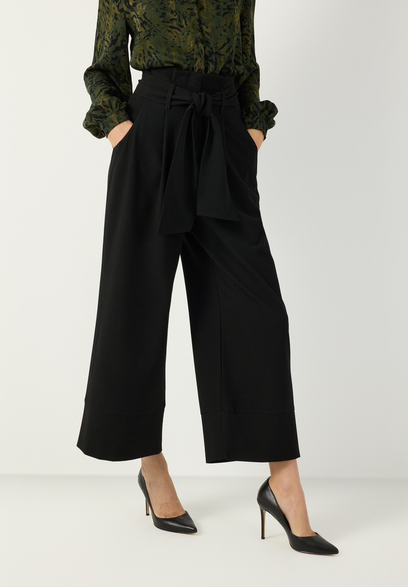 MORE & MORE schwarze Culotte-Hose mit hohem Bund und Bindegürtel, dazu dunkelgrüne Bluse mit Animal-Print. MORE & MORE schwarze Culotte-Hose mit hohem Bund und Bindegürtel, dazu dunkelgrüne Bluse mit Animal-Print.