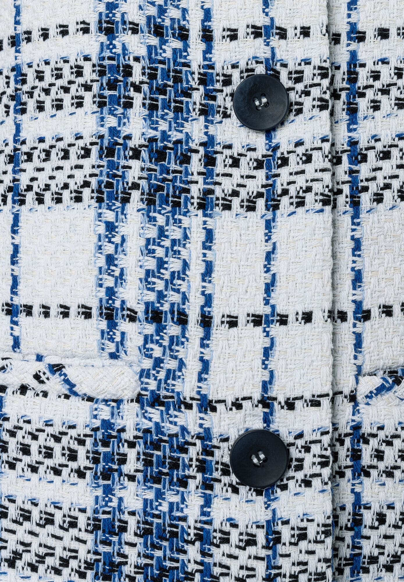 Detailaufnahme eines MORE & MORE Blazers mit Bouclé-Muster in Weiß, Blau und Schwarz, geschlossen mit zwei Knöpfen. Detailaufnahme eines MORE & MORE Blazers mit Bouclé-Muster in Weiß, Blau und Schwarz, geschlossen mit zwei Knöpfen.