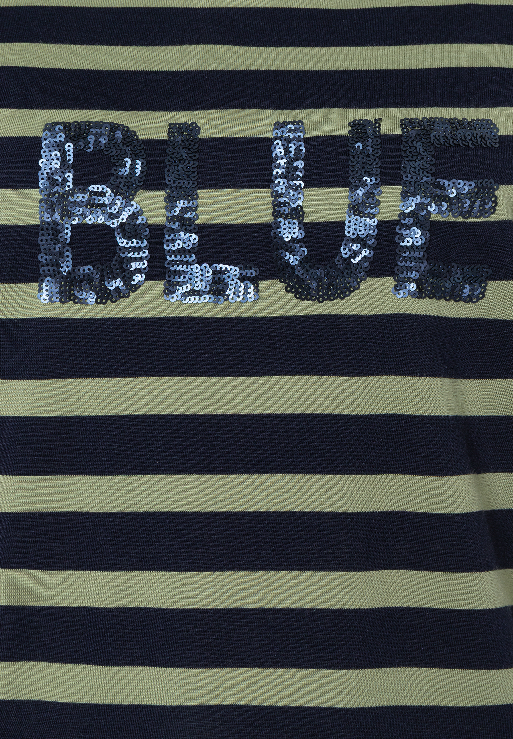 Nahaufnahme eines MORE & MORE Oberteils mit blauen Streifen und dem Wort "BLUE" aus Pailletten. Nahaufnahme eines MORE & MORE Oberteils mit blauen Streifen und dem Wort "BLUE" aus Pailletten.